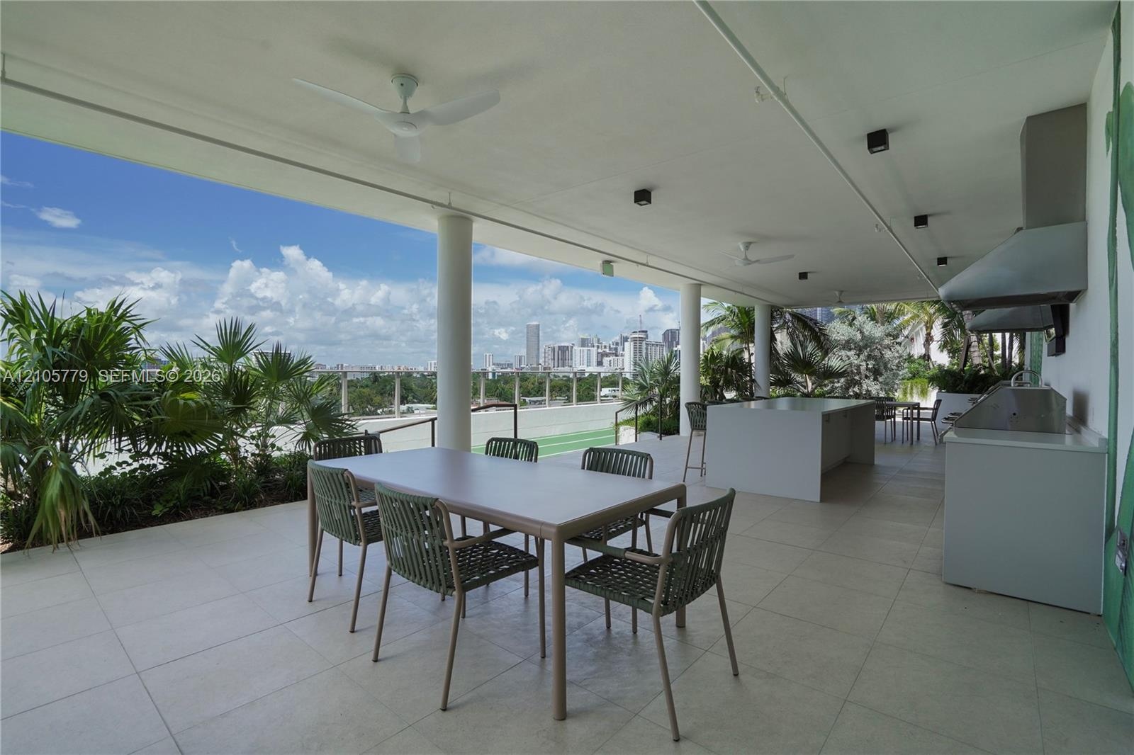 Covered terrace featuring large-format tile flooring, built-in outdoor kitchen with stainless steel grill, integrated ceiling fans, and structural col