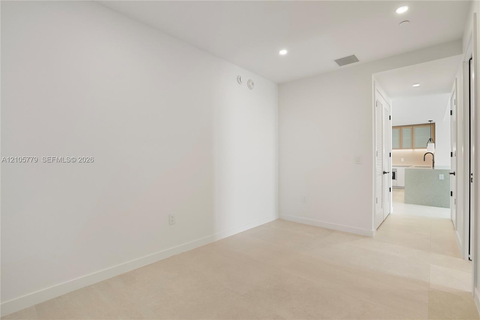 Neutral interior space featuring high-contrast recessed lighting, wall-to-wall carpeting, and crisp white finishes