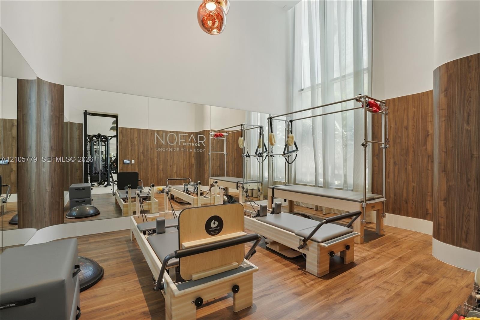 Double-height ceiling, floor-to-ceiling window, wood-finish wall paneling, full-wall mirror, and wood-finish flooring