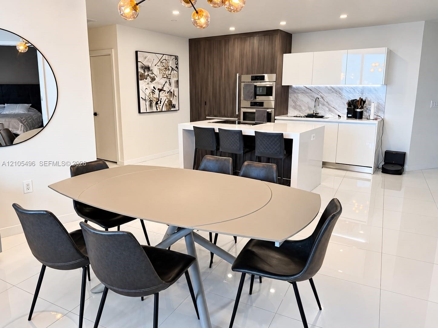Contemporary kitchen featuring a center island with a solid surface countertop, high-gloss white cabinetry, integrated stainless steel double wall ove