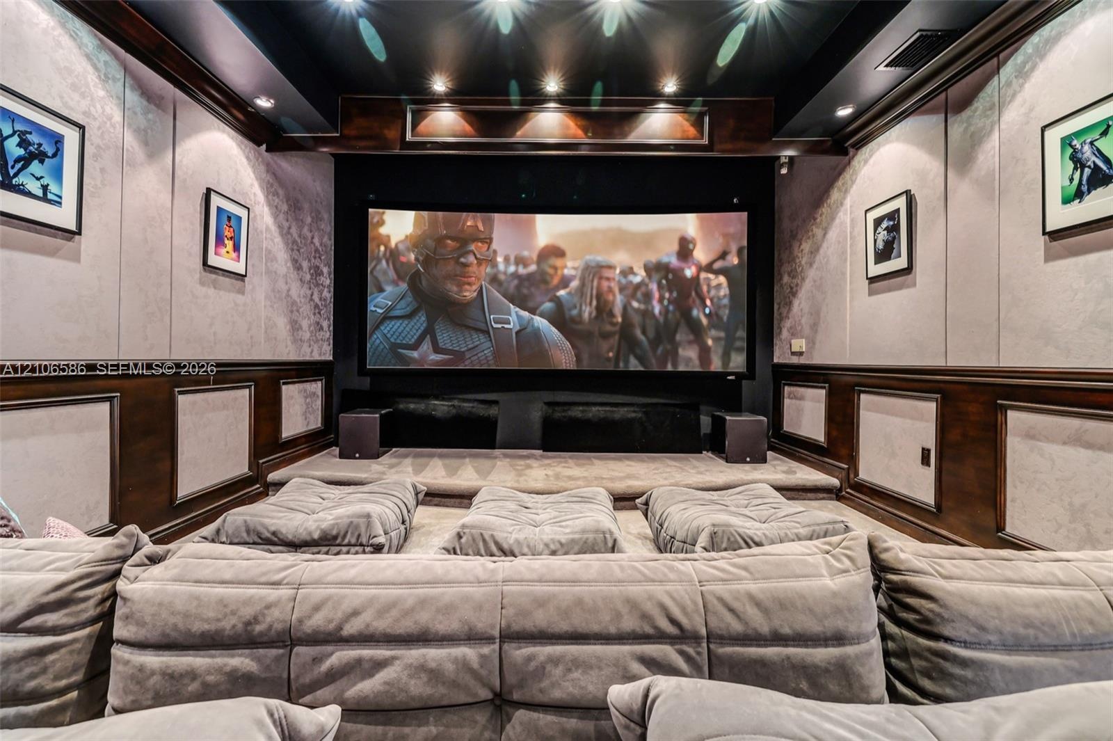 Dedicated screening room featuring a tiered floor, custom wood wainscoting, recessed ceiling lighting, and integrated wall paneling