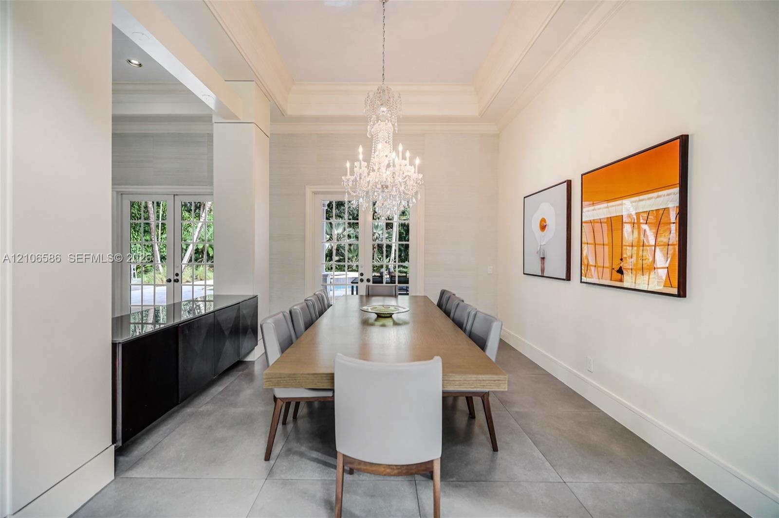 Formal room featuring a tray ceiling, crystal chandelier, large-format tile flooring, built-in cabinetry with a stone countertop, and multi-pane glass