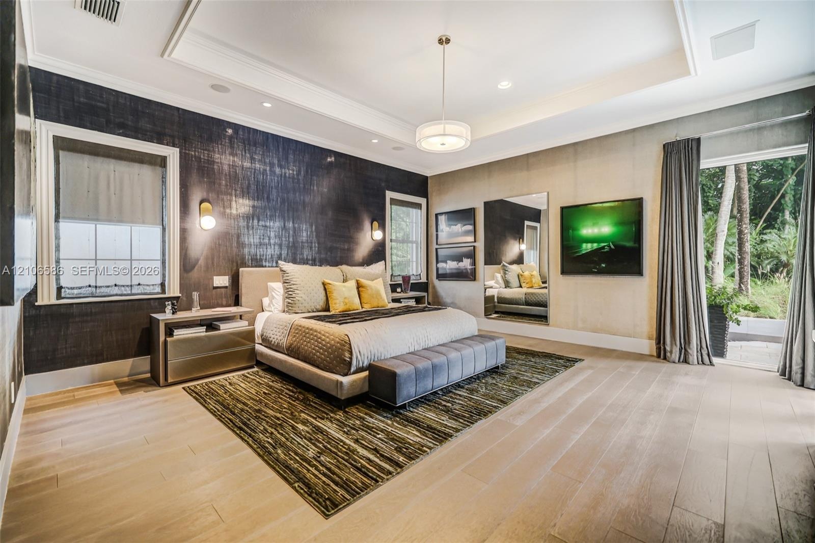 Tray ceiling with recessed lighting, wood-finish flooring, textured wall covering, wall-mounted accent lighting, and glass door entry to exterior spac