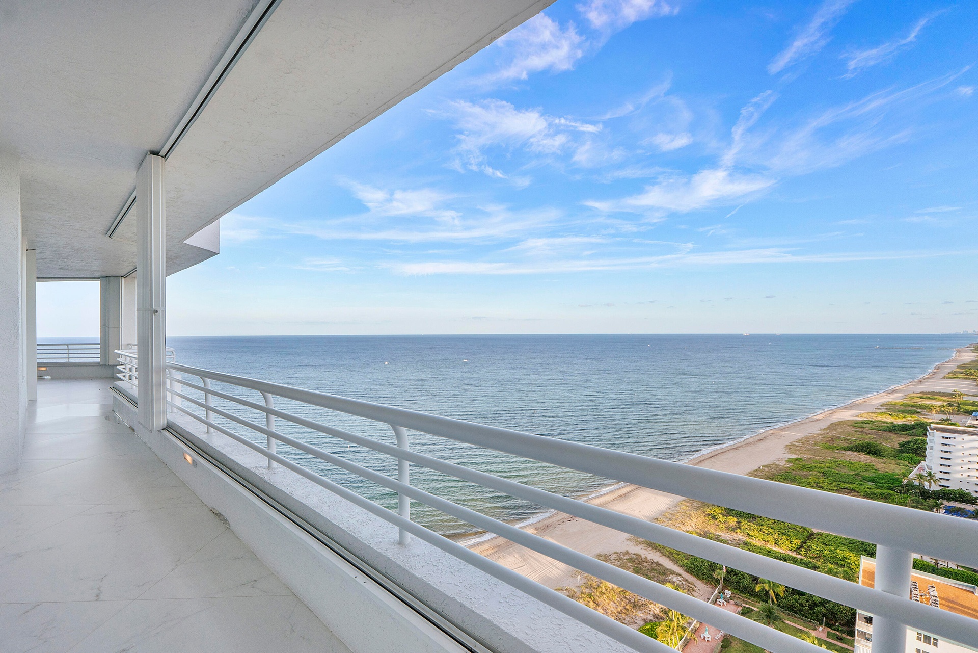 Looking south down the beach, the clouds are white and the sky compliments the ocean of sapphire