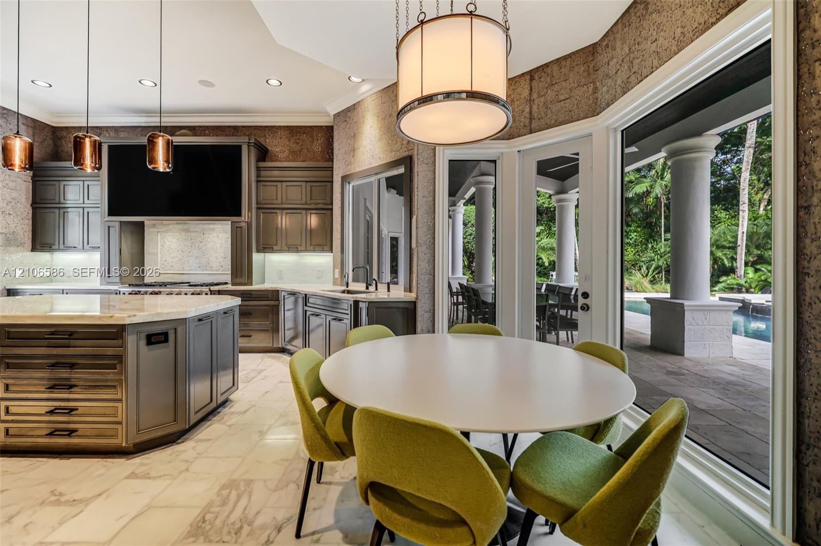 Kitchen featuring custom cabinetry, an oversized central island with stone countertop, large-format tile flooring, textured wall finishes, and expansi