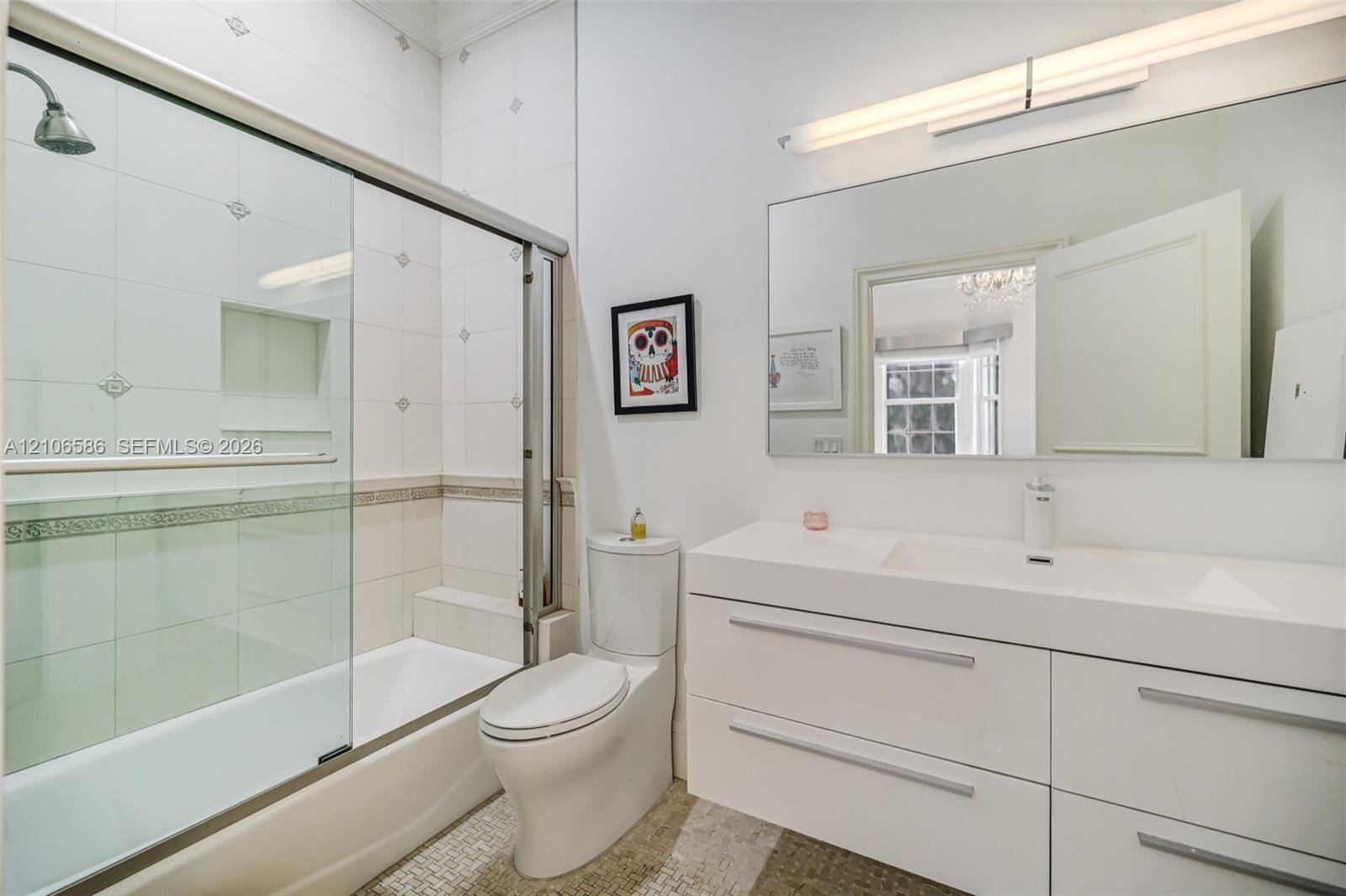Modern bathroom featuring a high-gloss double vanity with an integrated countertop, large-format tiled walls with decorative inlay, built-in shower ni