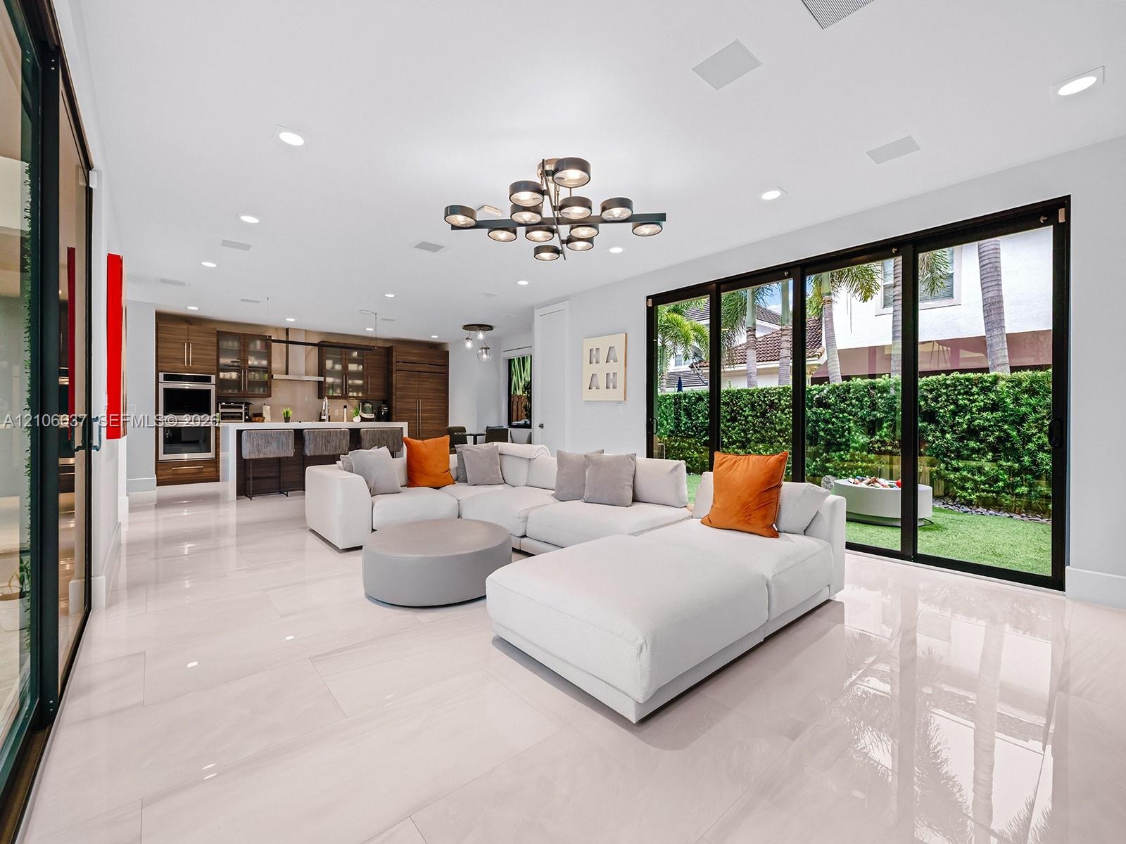 Open-concept living space featuring large-format tile flooring, multi-panel sliding glass doors, built-in cabinetry, recessed lighting, and a modern t