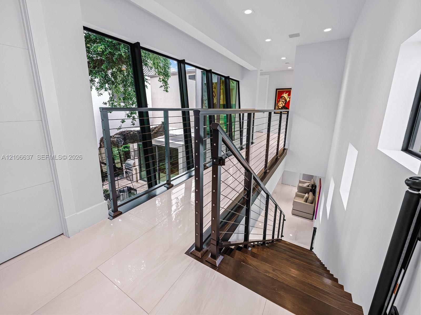 Staircase featuring dark wood treads, floor-to-ceiling windows, stainless steel cable railings, and polished tile flooring