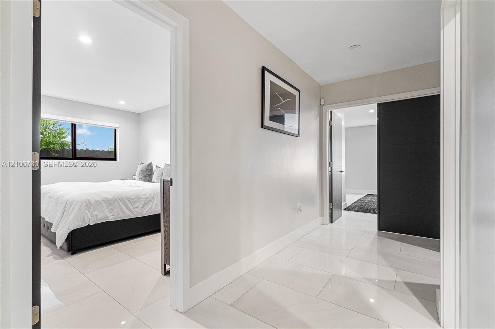 Large-format polished tile flooring, neutral wall tones, recessed lighting, and dark-finish interior doors