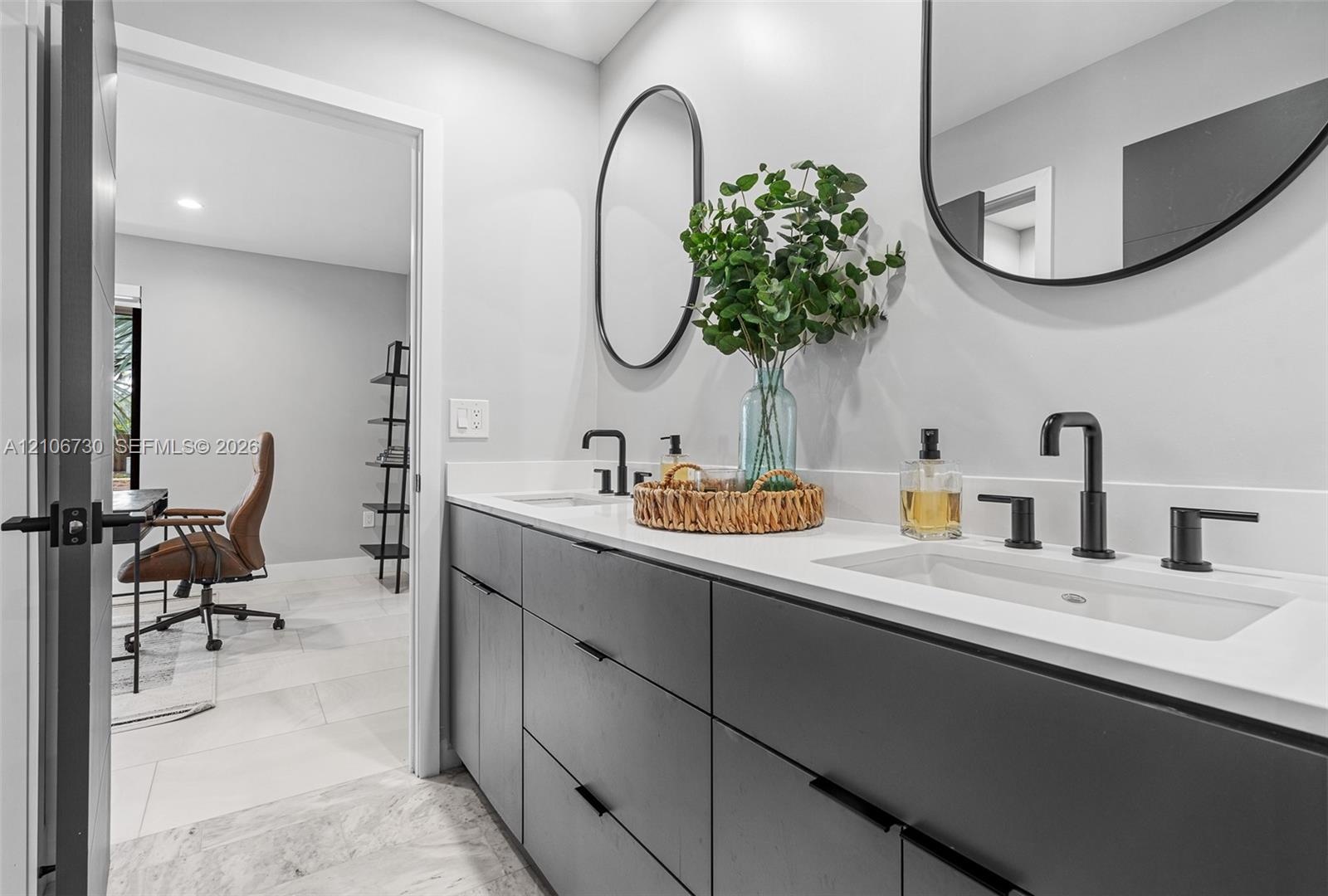 Modern dual-sink vanity featuring matte black hardware, integrated cabinetry with flat-panel doors, solid surface countertops, and dual wall-mounted o