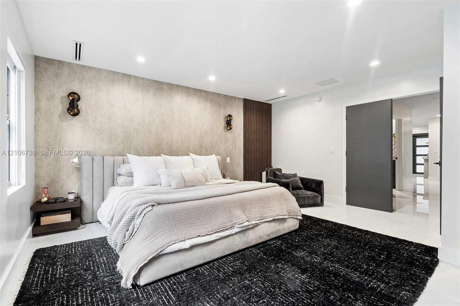 Textured stone accent wall, wood-slat feature paneling, recessed ceiling lighting, wall-mounted spherical light fixtures, and oversized dark-finish do