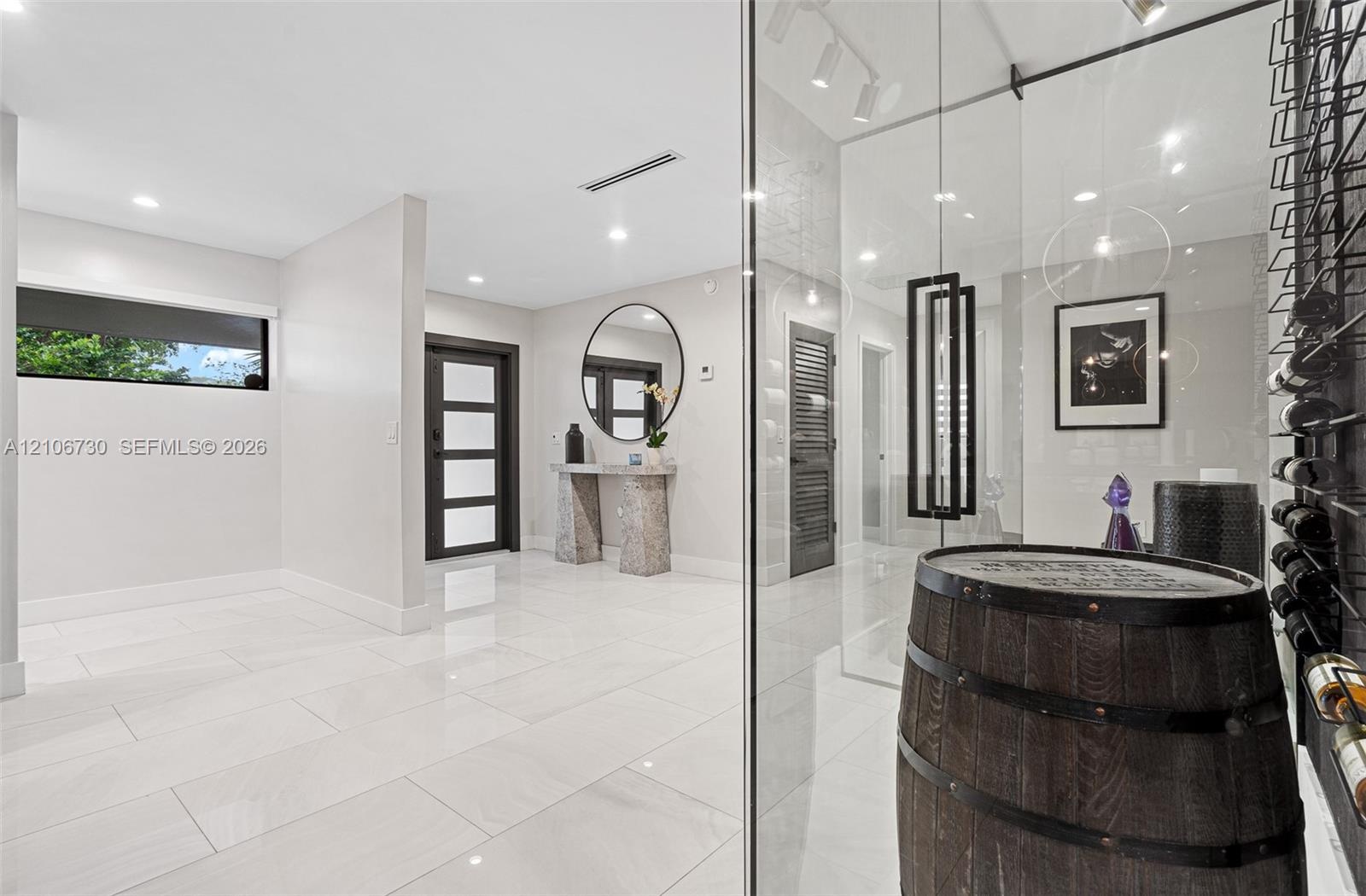 Entryway featuring large-format light tile flooring, recessed ceiling lighting, a dark-framed multi-panel front door, and a climate-controlled glass-e