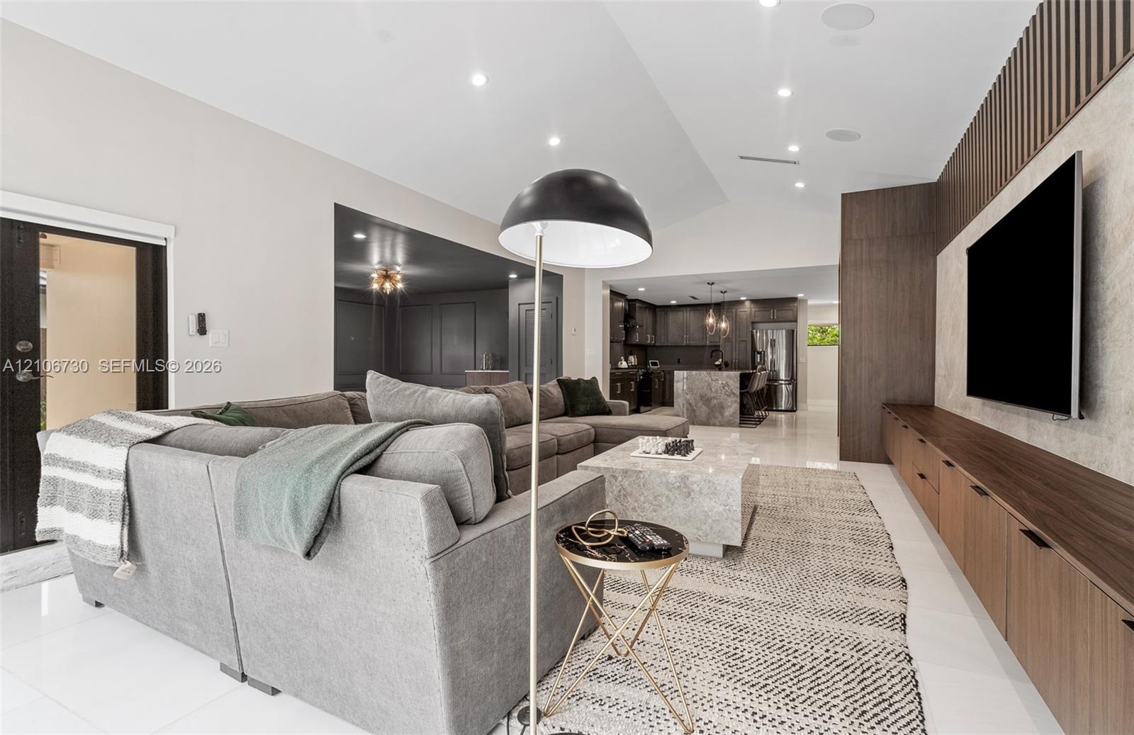 Living area featuring porcelain tile flooring, built-in wall-to-wall wood cabinetry, vertical wood slat wall detailing, and recessed ceiling lighting