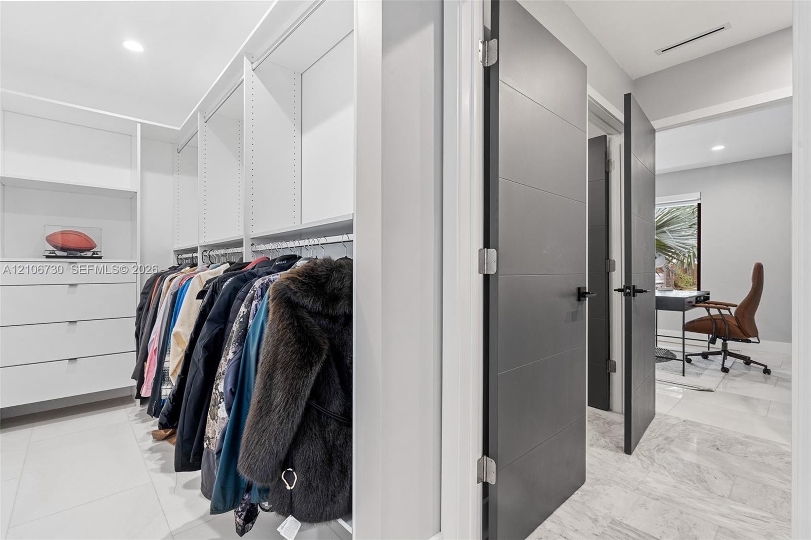 Custom walk-in closet featuring white built-in shelving, integrated storage drawers, and contemporary charcoal-toned interior doors with matte black h