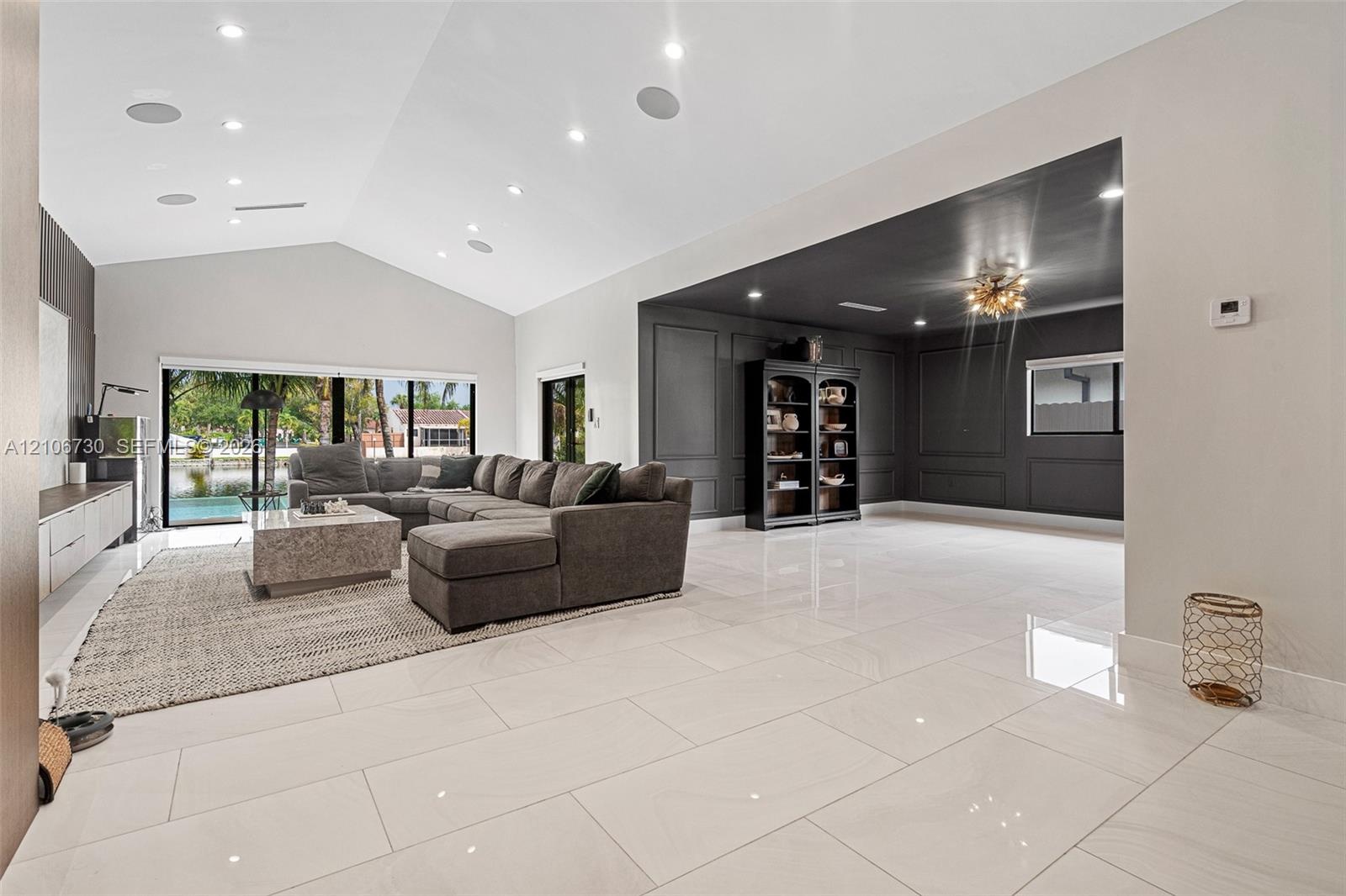 Open-concept interior featuring vaulted ceilings, oversized tile flooring, recessed lighting, and expansive glass sliding doors