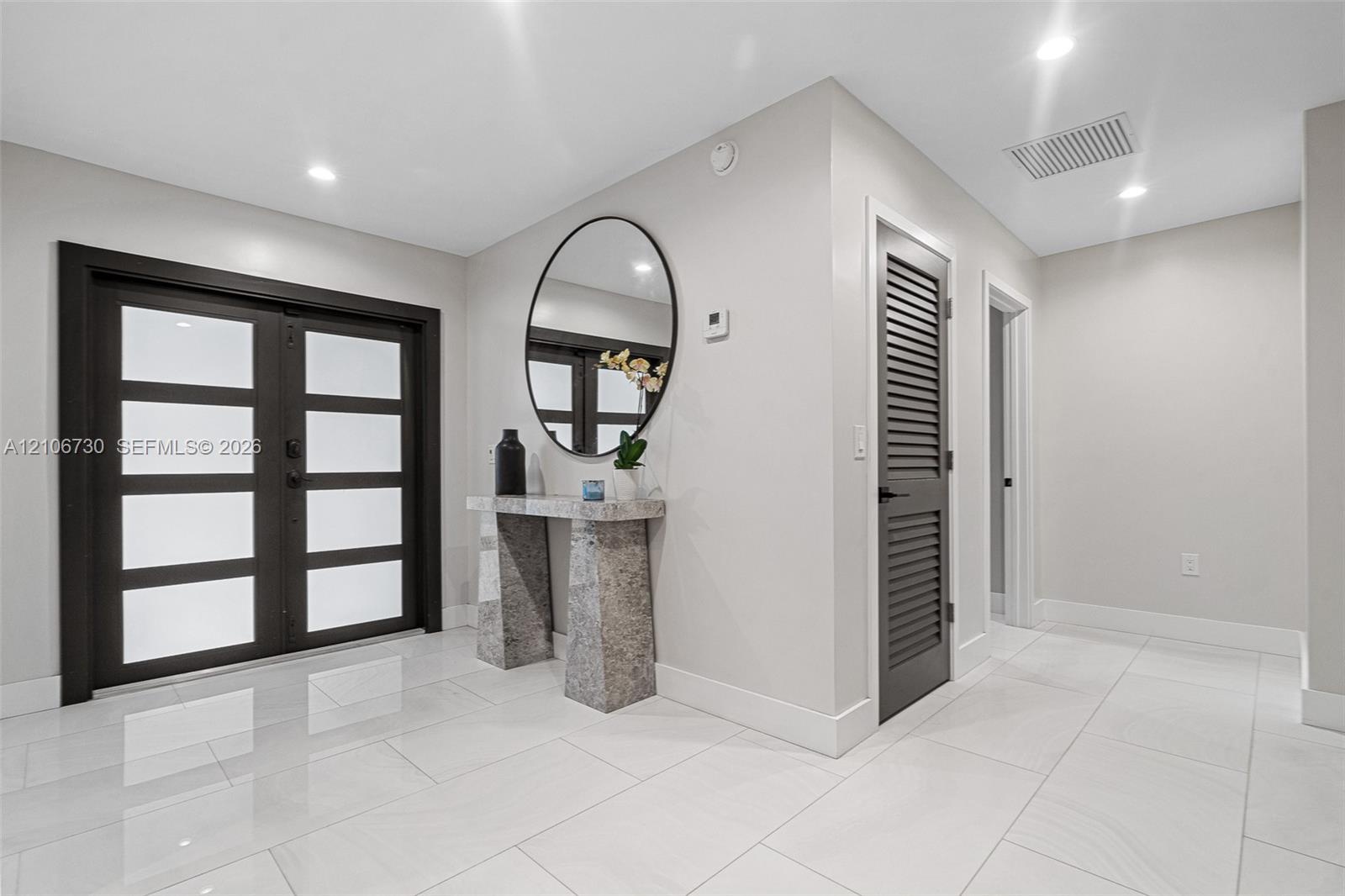 Foyer featuring double-entry doors with frosted glass panels, polished tile flooring, recessed lighting, and a louvered door