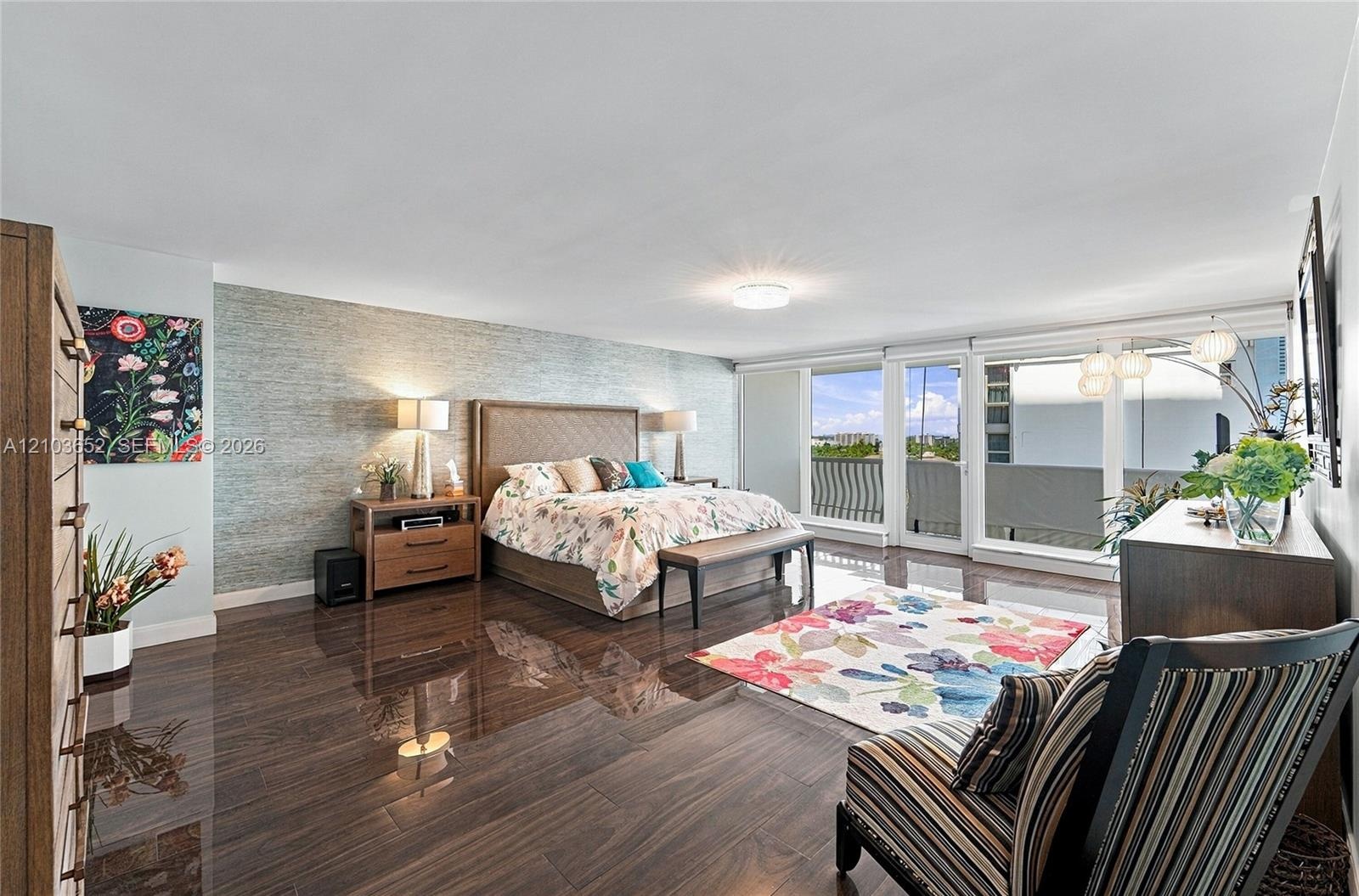 Wood-finish flooring, textured accent wall, and expansive glass sliding doors providing external access