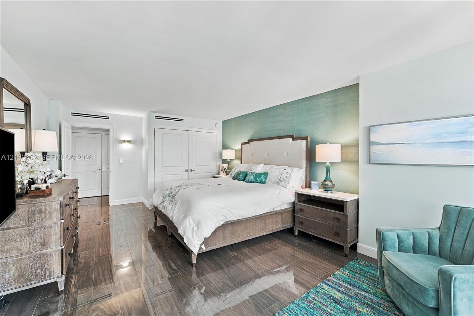 Wood-finish tile flooring, textured teal accent wall, recessed ceiling lighting, and double-door closets