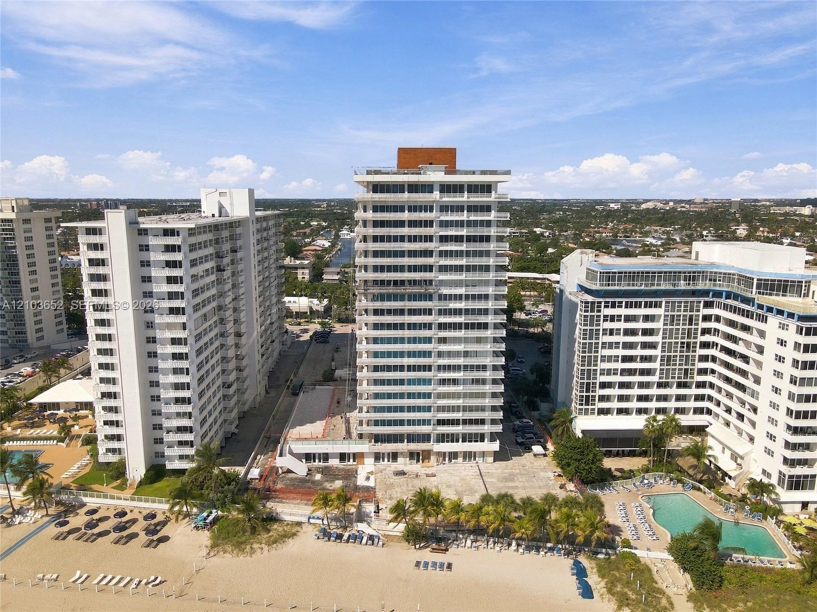 High-rise residential building featuring expansive glass balcony railings, a flat roofline, and direct sandy beach access