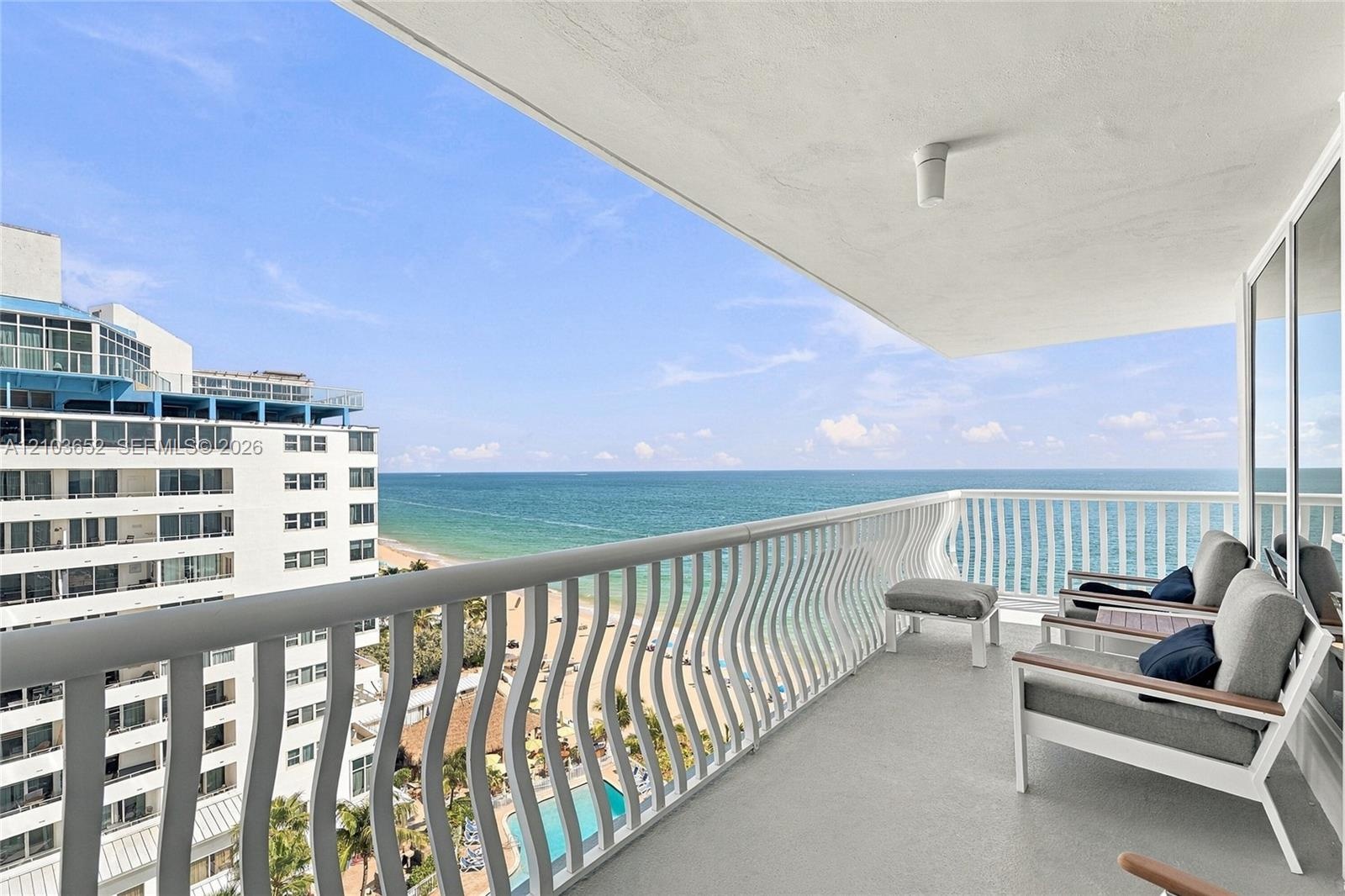 Covered balcony with white metal serpentine railing, concrete flooring, and unobstructed water scenery