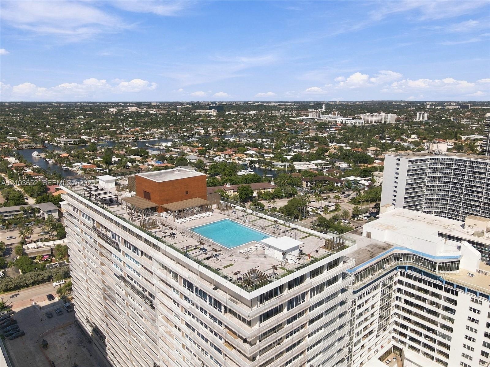 Rooftop terrace featuring a swimming pool, shaded pergola structure, and glass perimeter railings