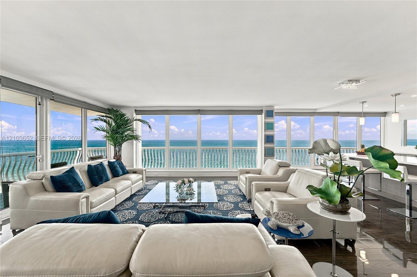 Open-concept living space featuring floor-to-ceiling glass wall panels, wood-finish flooring, recessed lighting, and a kitchen island with pendant lig