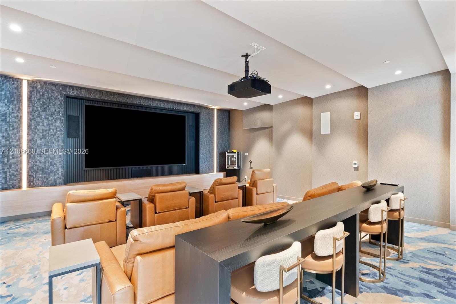 Media space featuring a recessed wall display, integrated vertical accent lighting, textured wall coverings, and a ceiling-mounted projection system