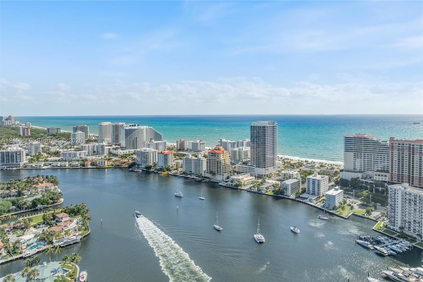 Panoramic coastal scenery featuring a waterway, maritime traffic, beachfront high-rise buildings, and an open ocean horizon