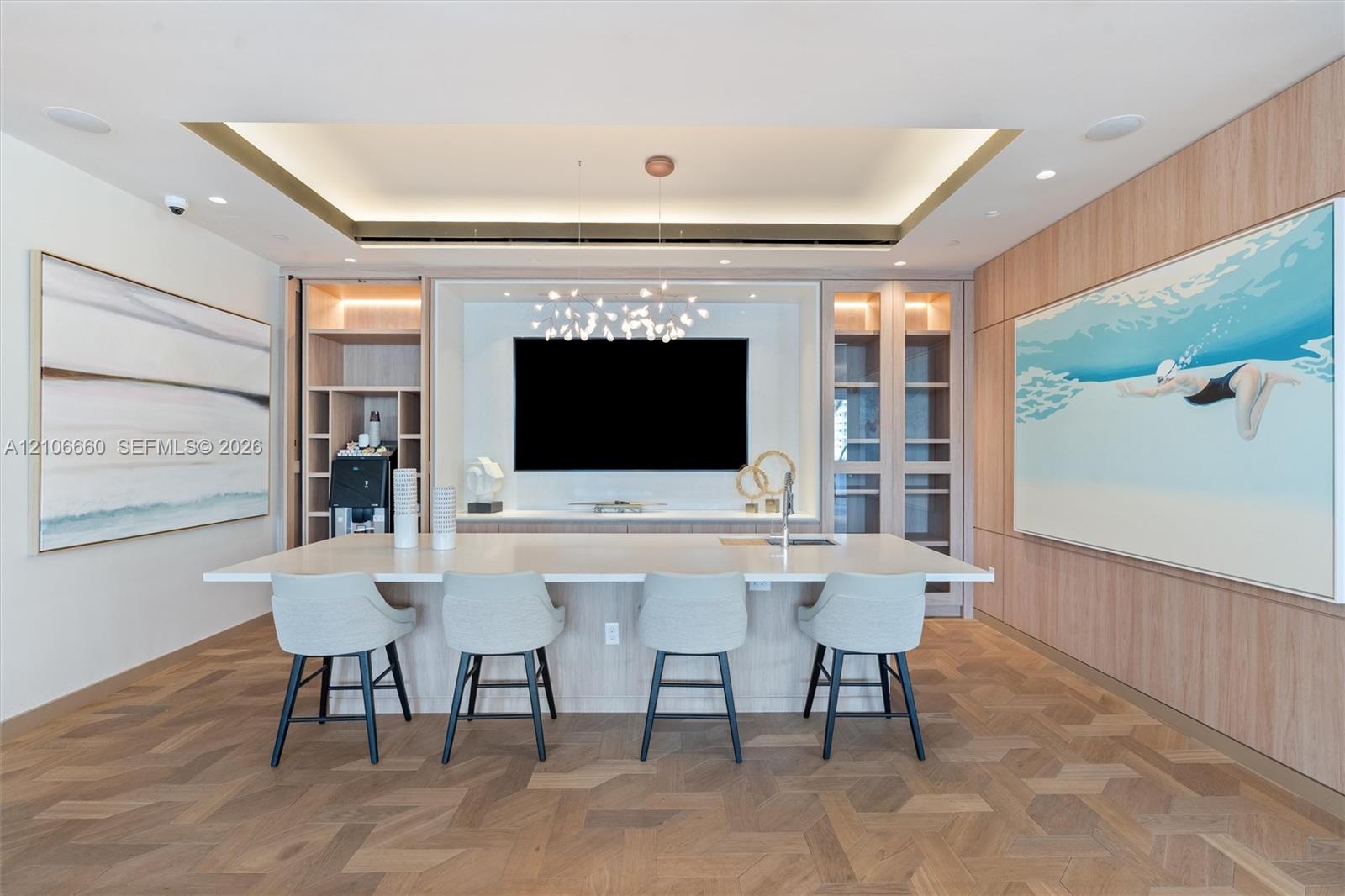 Custom millwork wall unit with built-in cabinetry and display shelving, integrated wet bar with sink, tiered tray ceiling with recessed lighting, and 