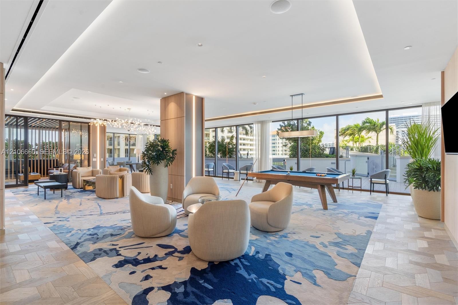 Expansive open-concept space featuring herringbone-patterned wood-finish flooring, floor-to-ceiling glass paneling, recessed cove lighting, and floor-