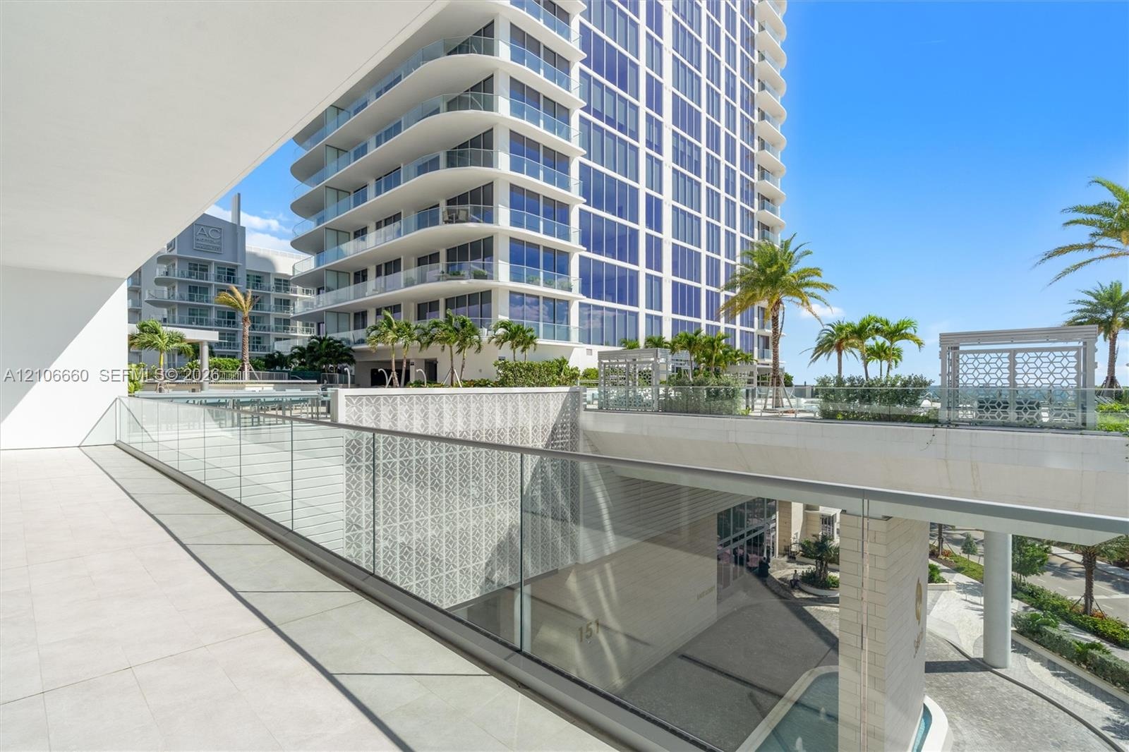 Covered terrace featuring glass panel railings, large-format tile flooring, and decorative metal screen privacy panels