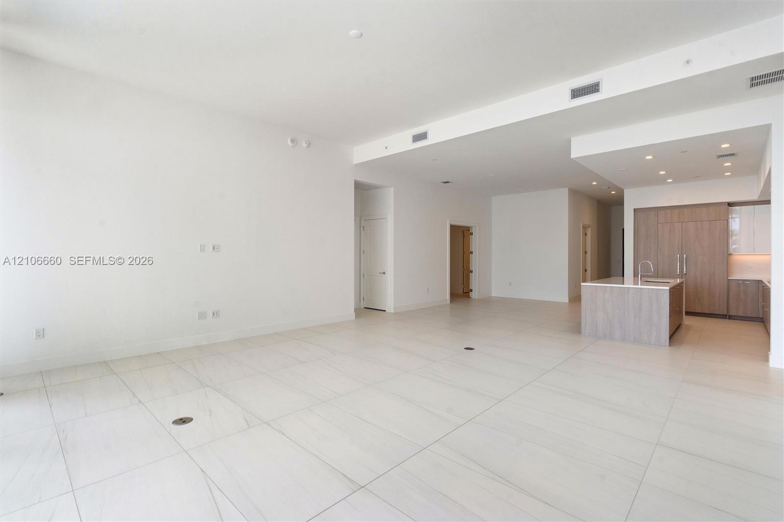 Open-concept interior featuring large-format tile flooring, recessed ceiling lighting, and a kitchen island with stone countertops
