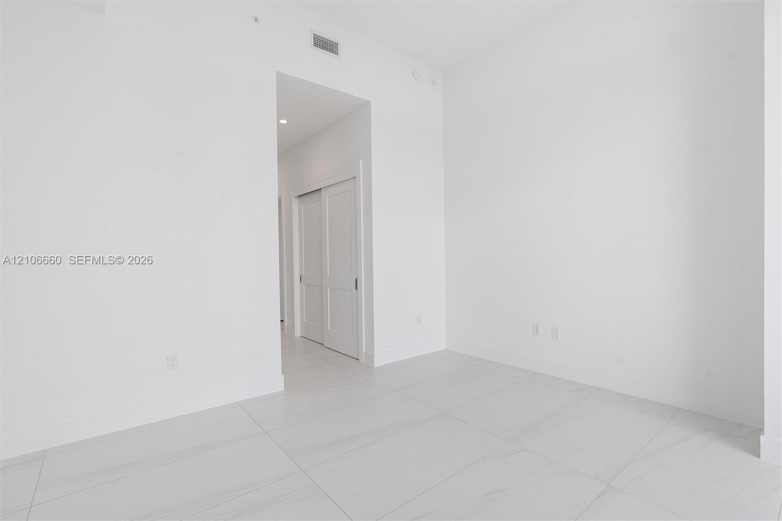 Interior space featuring large-format rectified tile flooring, recessed ceiling lighting, and double-panel sliding closet doors