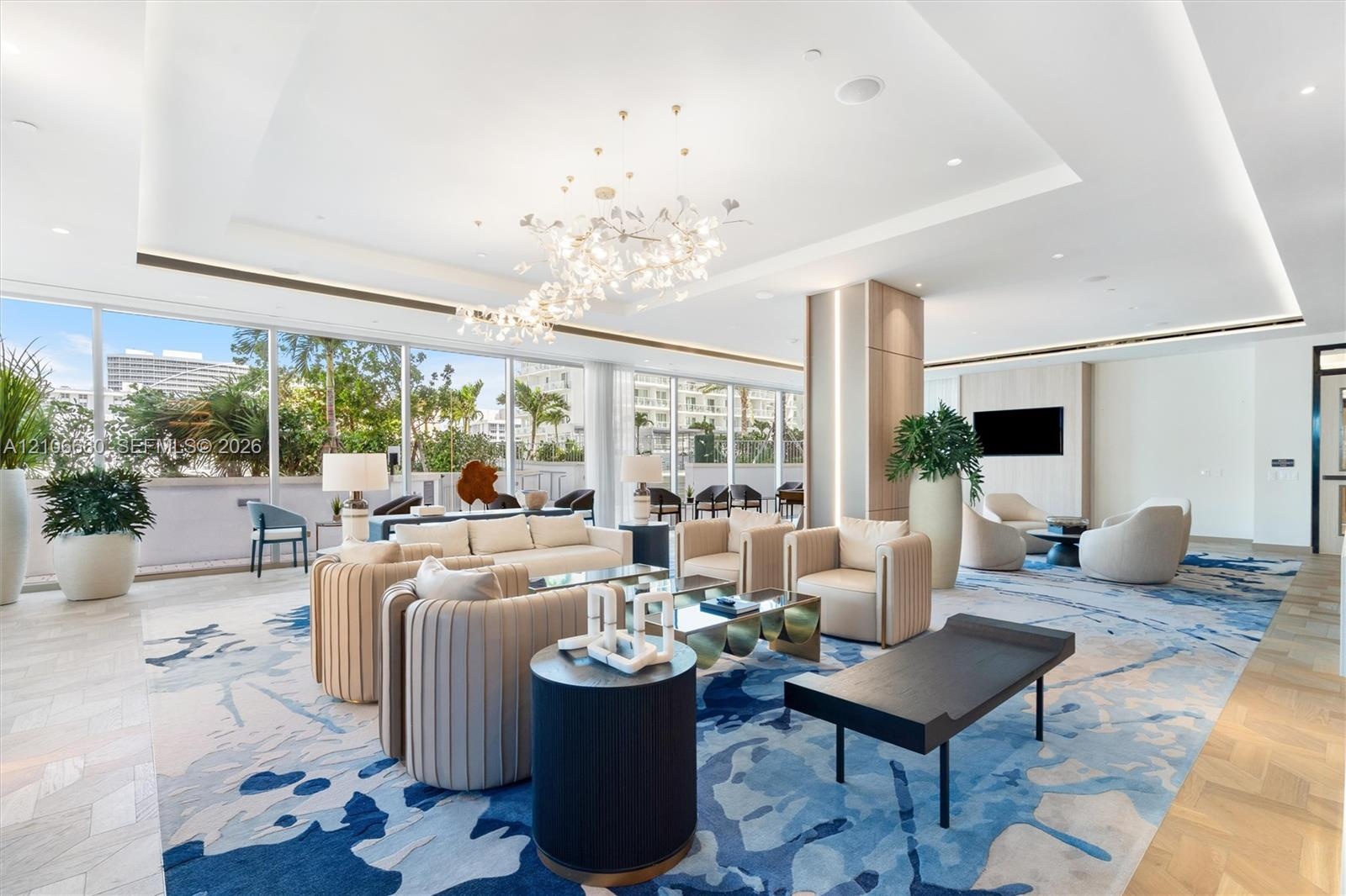Expansive living space featuring floor-to-ceiling glass windows, recessed tray ceilings, decorative chandelier lighting, wood-finish herringbone floor