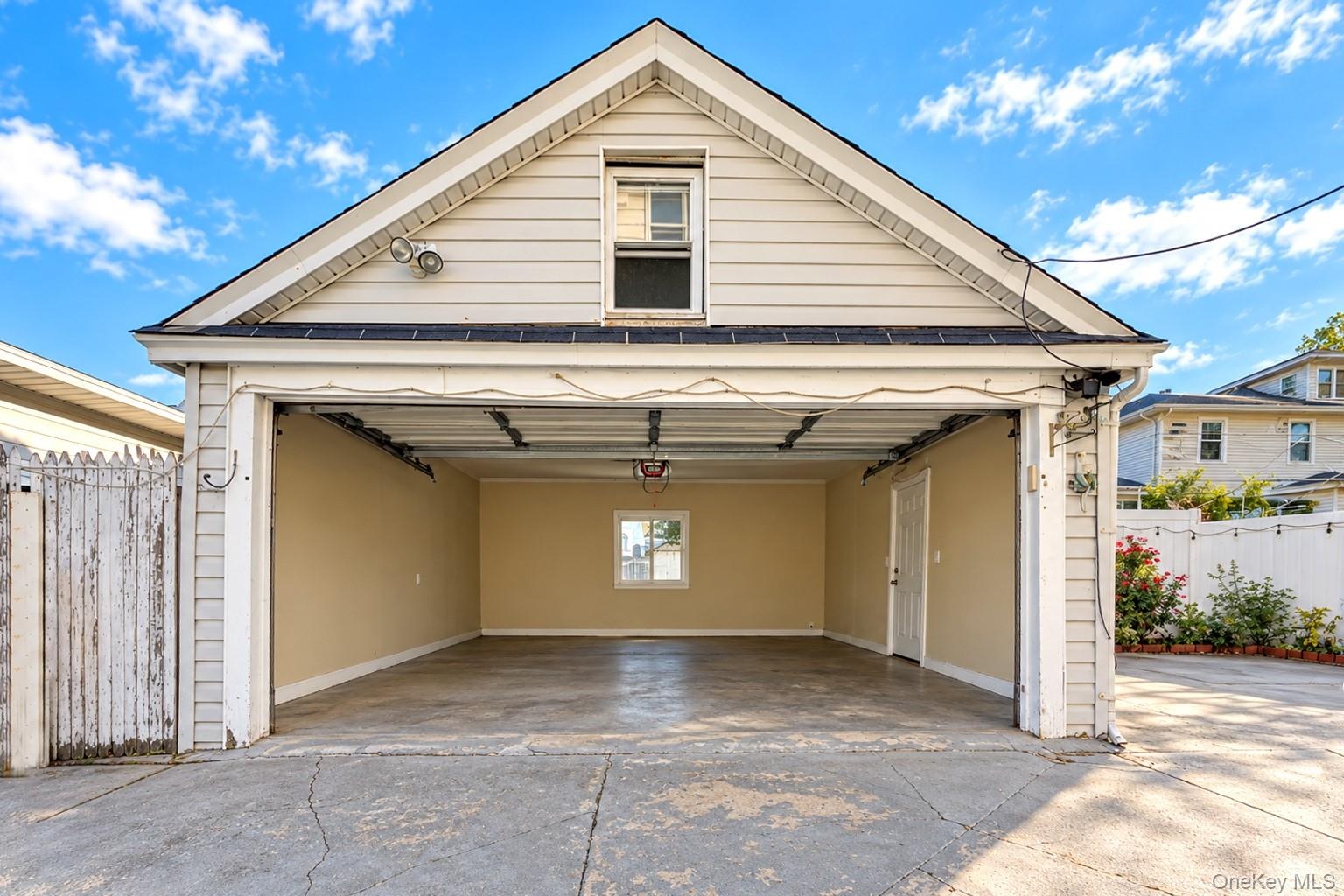 Detached garage featuring horizontal lap siding, an overhead garage door, a single-entry side door, and a dedicated storage area accessible via a gabl