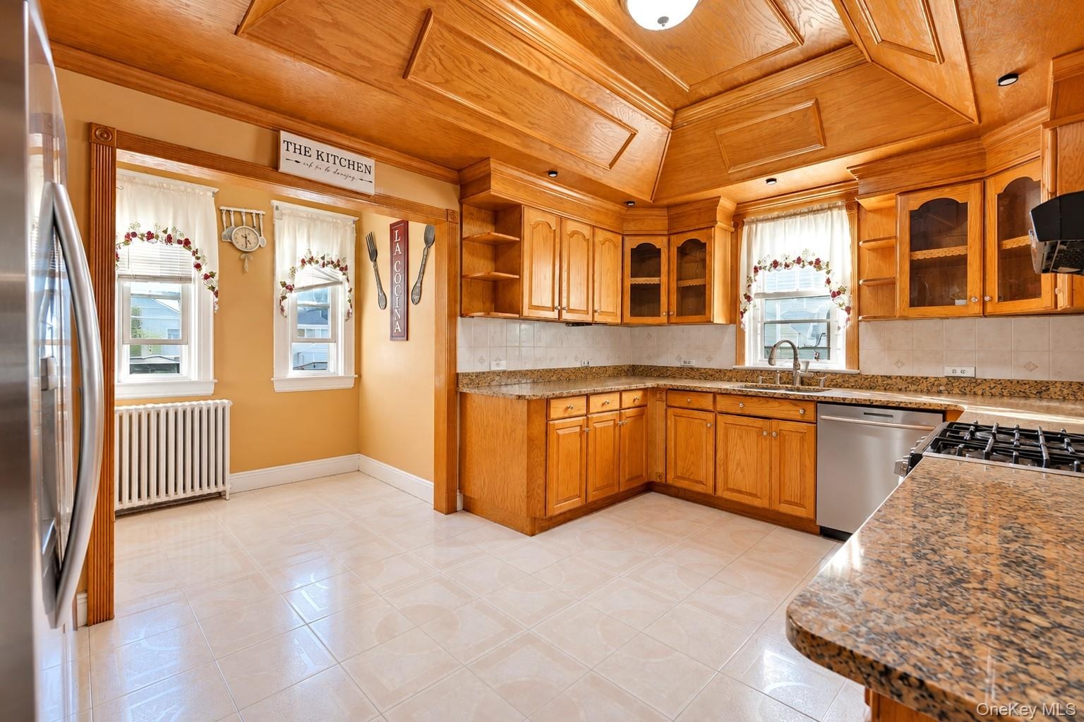 Kitchen featuring natural wood cabinetry, vaulted wood-paneled ceiling, stone-surface countertops, tile flooring, and stainless steel dishwasher