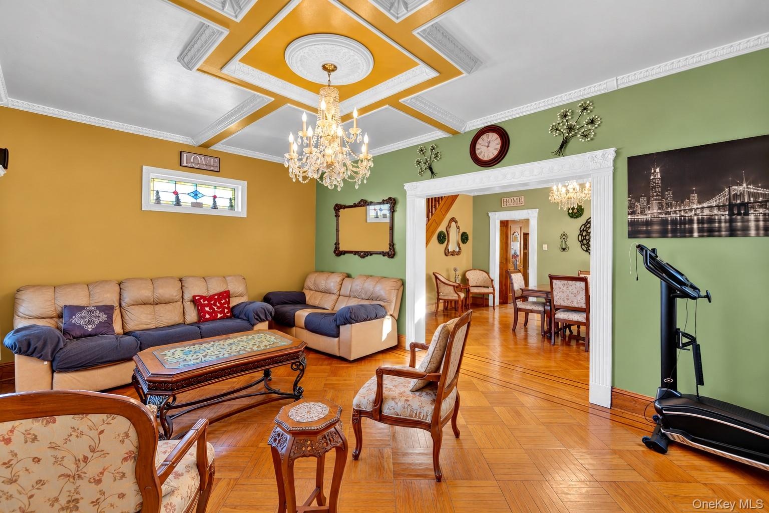 Coffered ceiling with decorative molding, intricate wood-finish parquet flooring, crystal chandelier, and stained-glass window accent