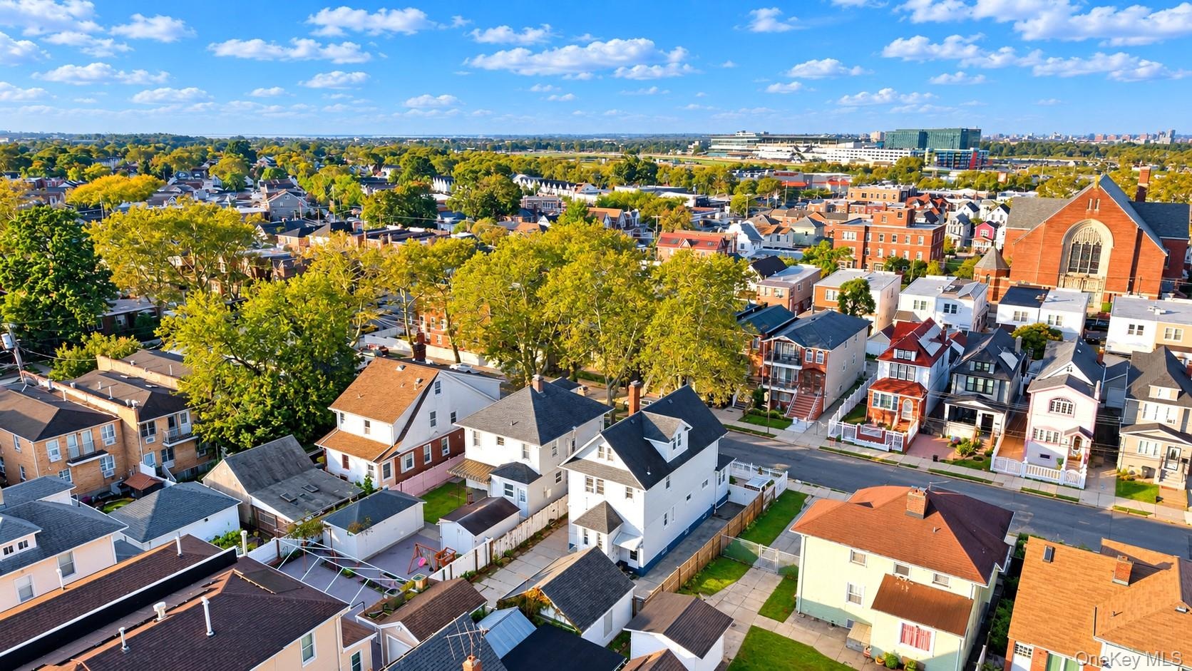 Aerial perspective of a residential neighborhood featuring mature tree-lined streets, diverse architectural styles, and proximity to regional infrastr