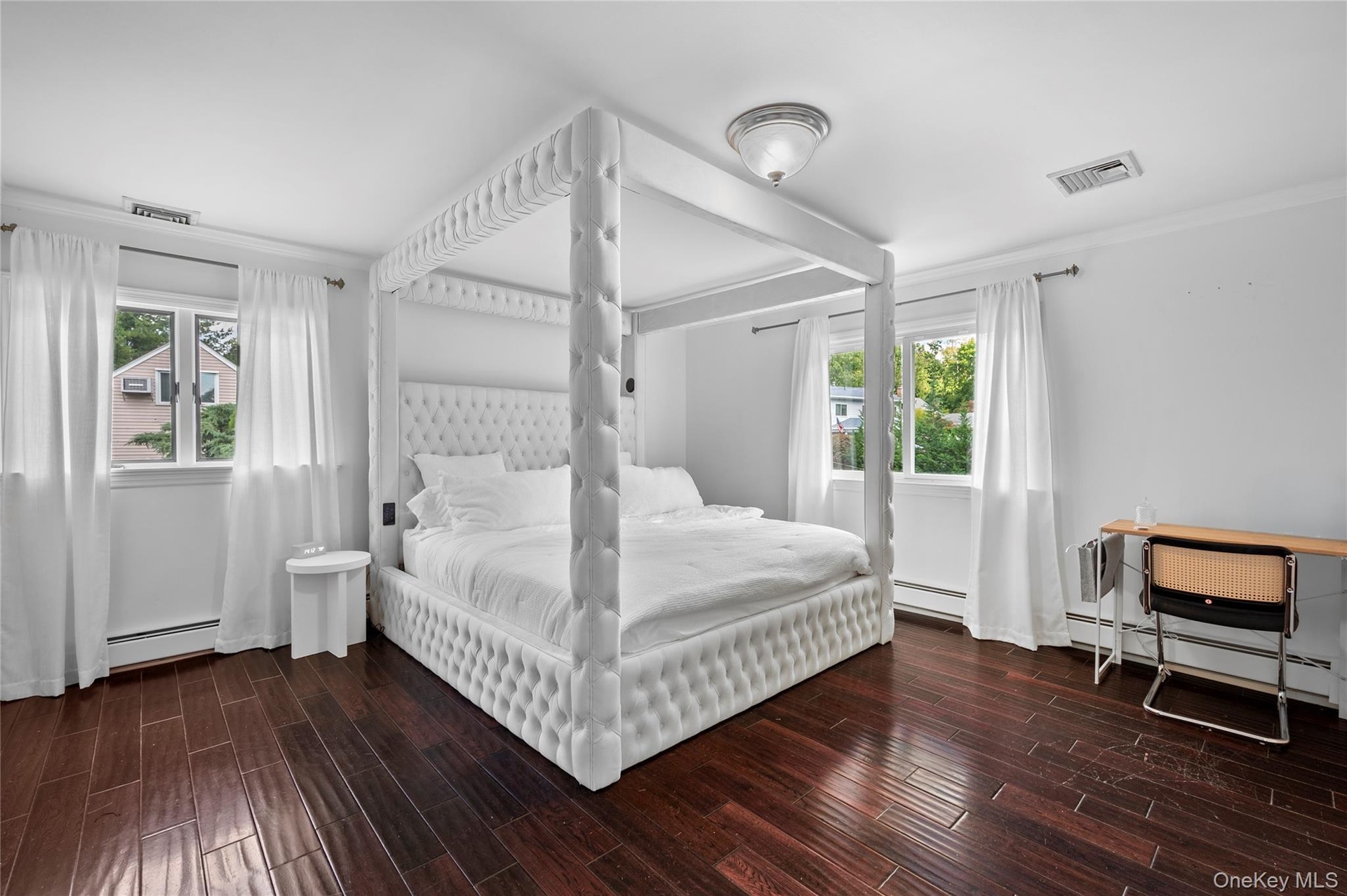 Wood-finish flooring, dual windows with curtain rods, and a ceiling-mounted light fixture