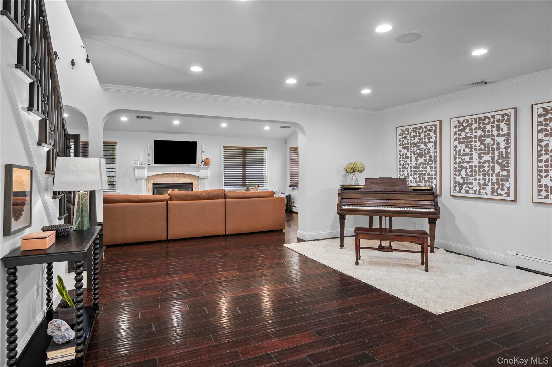 Dark wood-finish flooring, recessed lighting, arched wall opening, and a fireplace with a decorative mantel
