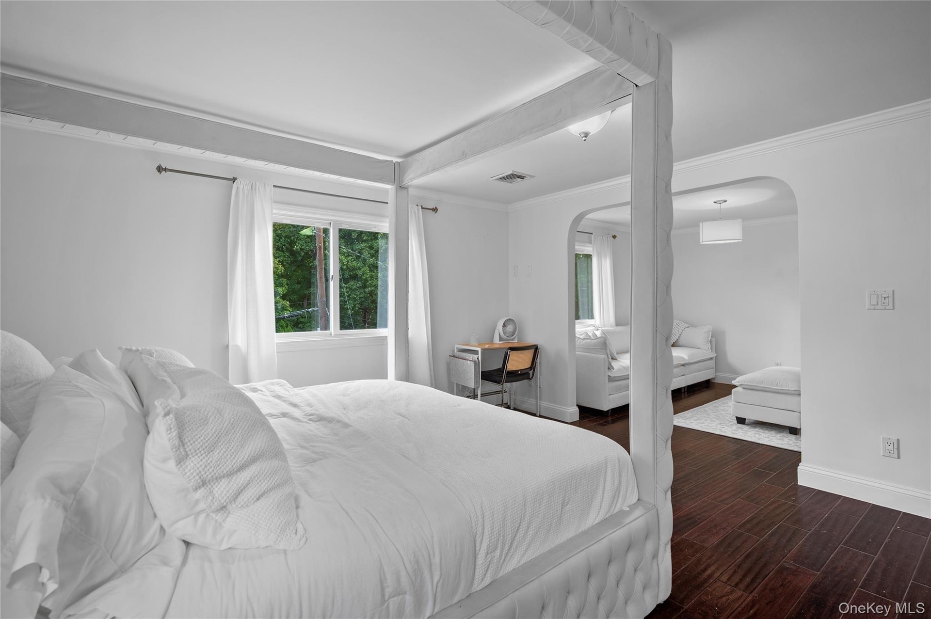 Dark wood-finish flooring, arched entryway, and crown molding