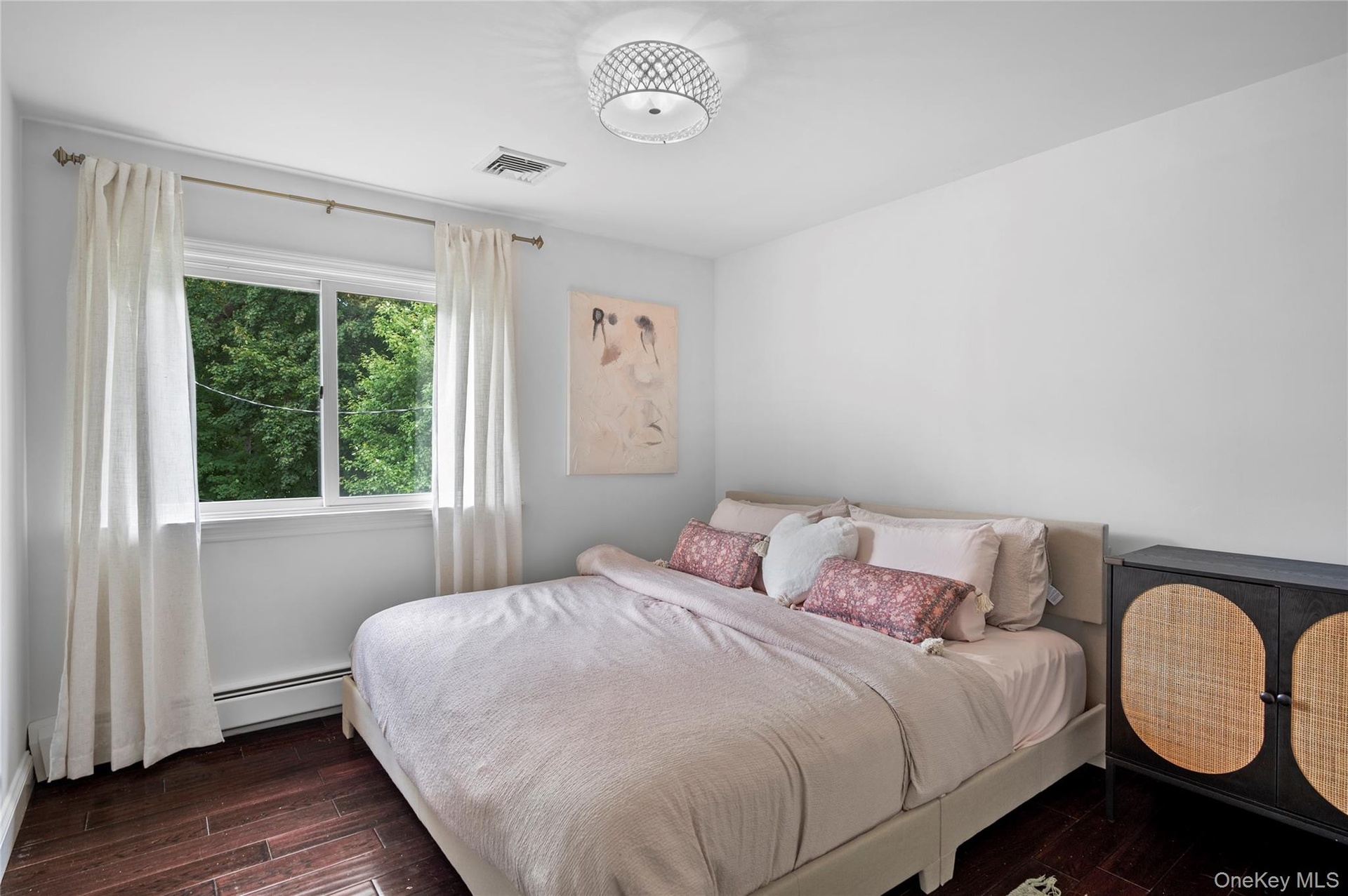 Bedroom featuring wood-finish flooring, a large sliding window, and a decorative semi-flush mount ceiling fixture