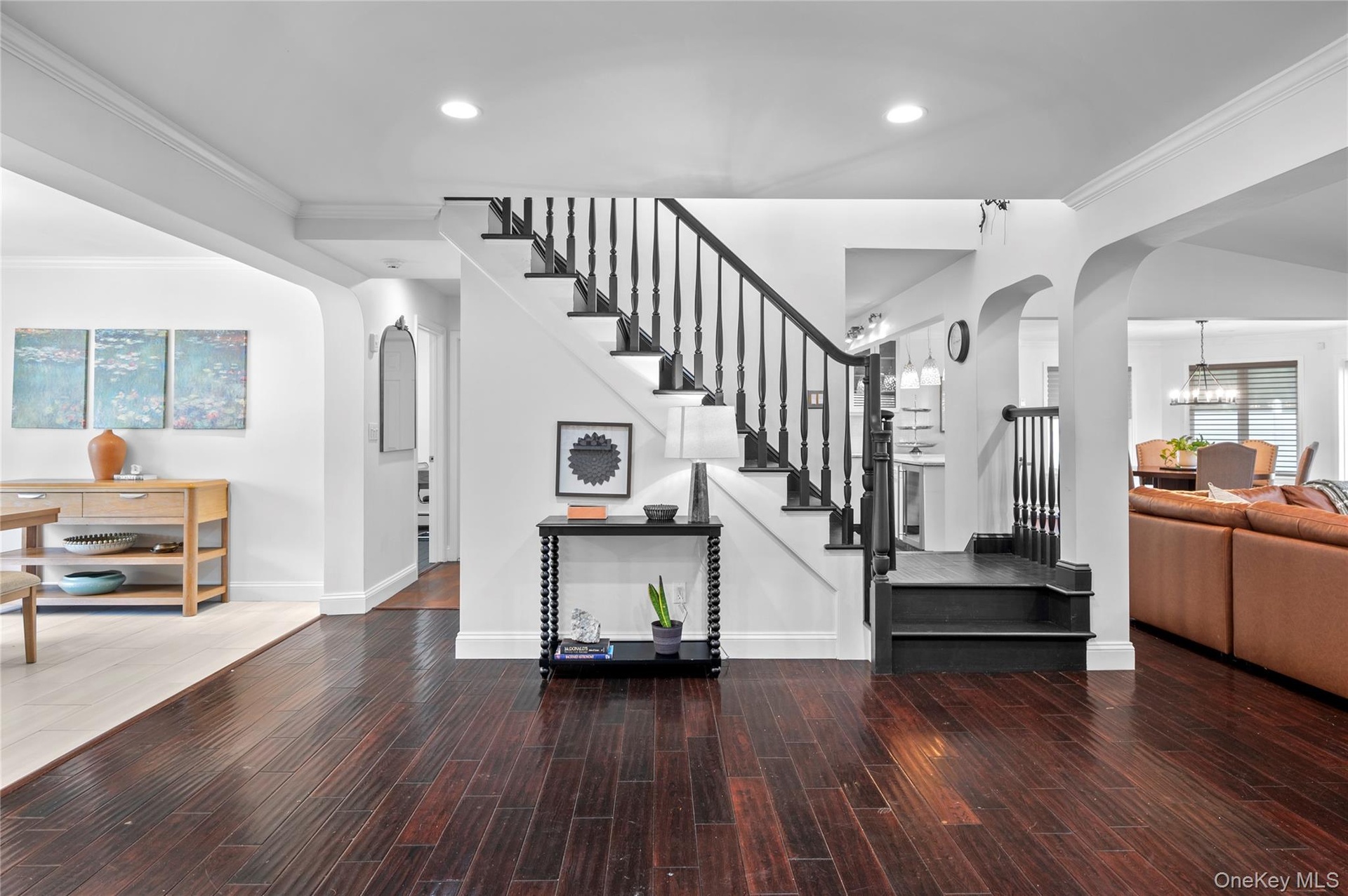 Staircase featuring dark-stained wood treads, matching handrail, and white risers, complemented by deep-toned hardwood flooring and recessed lighting