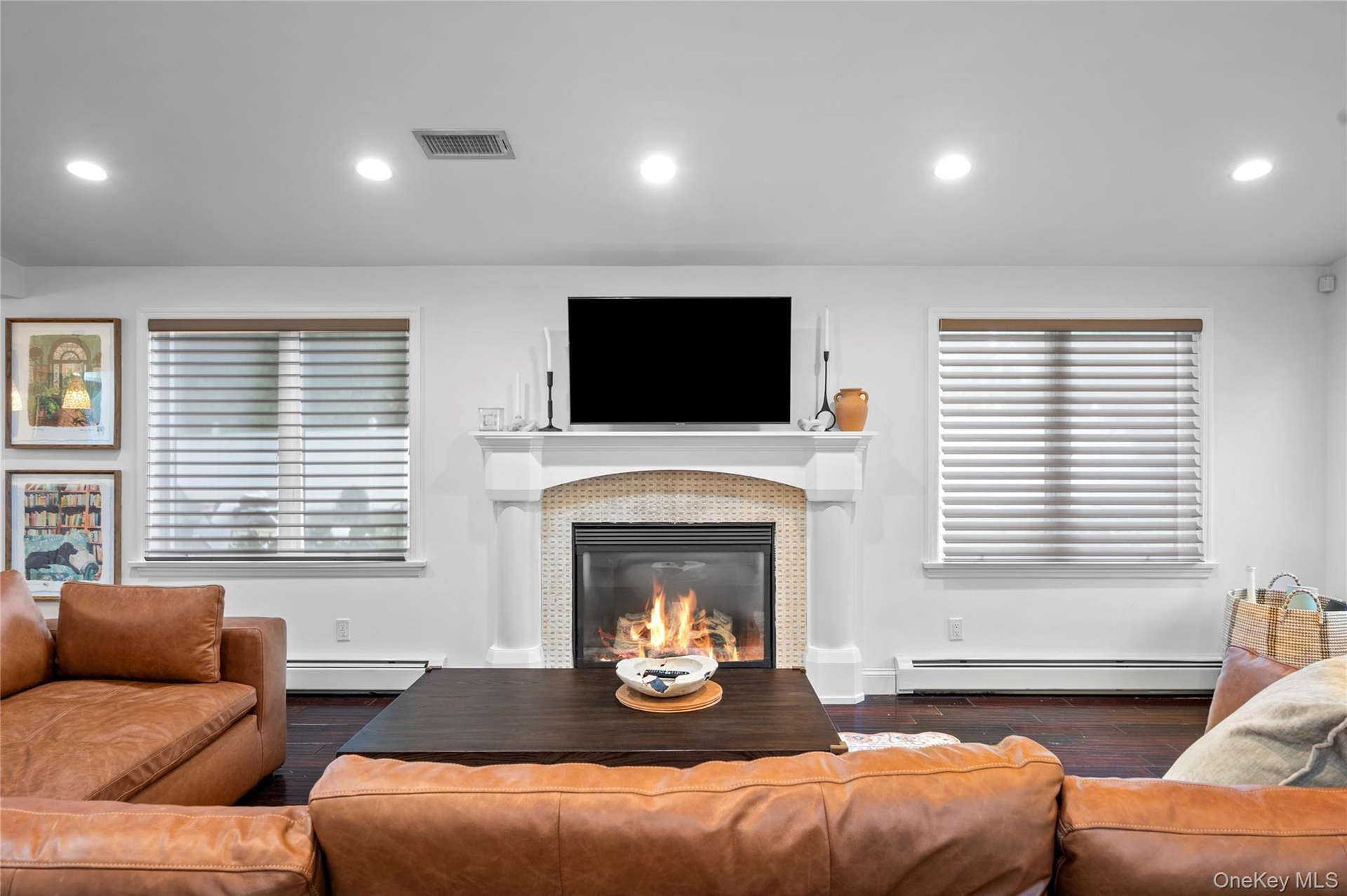 Fireplace featuring a mosaic tile surround, decorative columns, and a mantle, accented by dark wood-finish flooring and recessed lighting