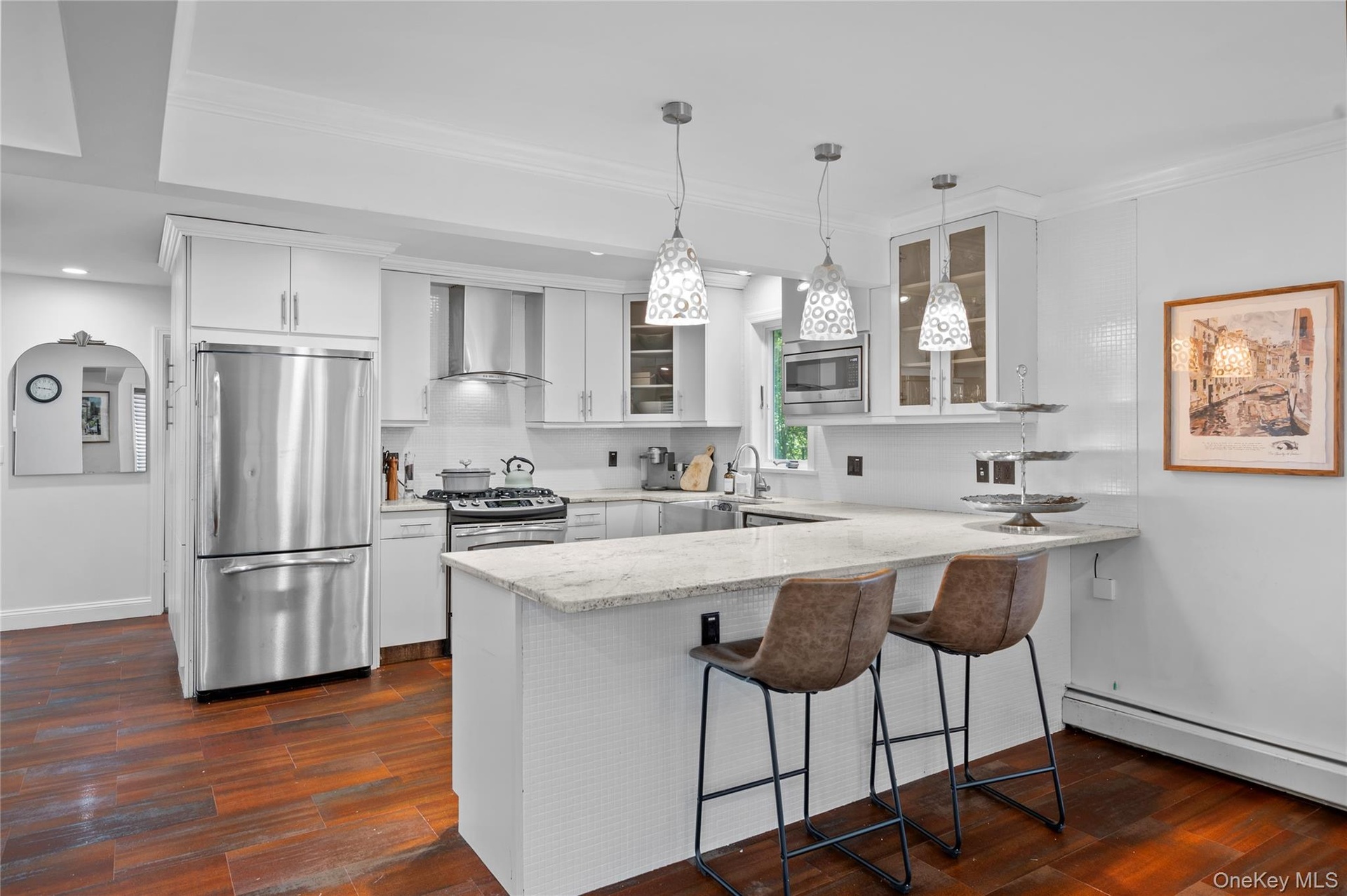 Kitchen featuring white cabinetry, stone countertops, stainless steel appliances, wood-finish flooring, and three glass pendant lights