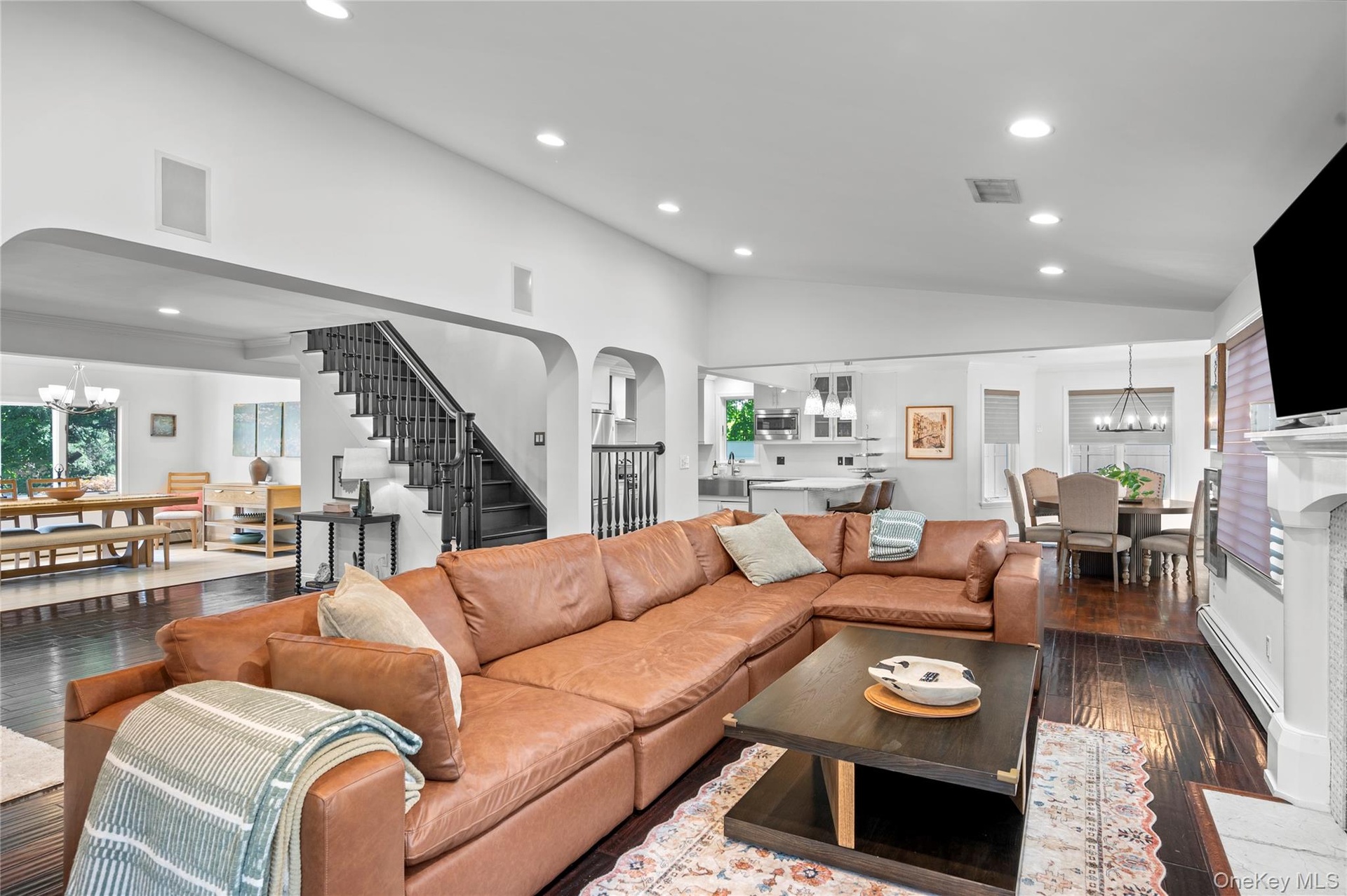 Vaulted ceilings, wood-finish flooring, recessed lighting, and a fireplace with a decorative mantle