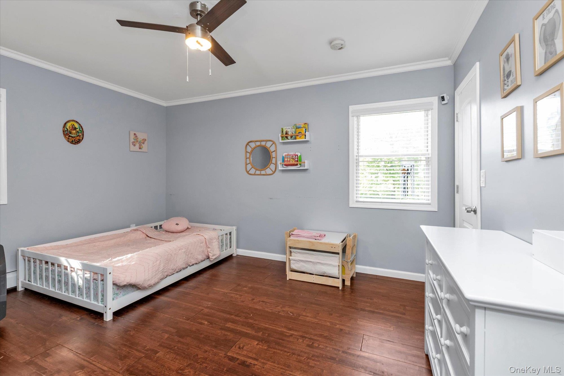 Room featuring wood-finish flooring, a ceiling fan with integrated lighting, and a single-pane window with horizontal blinds