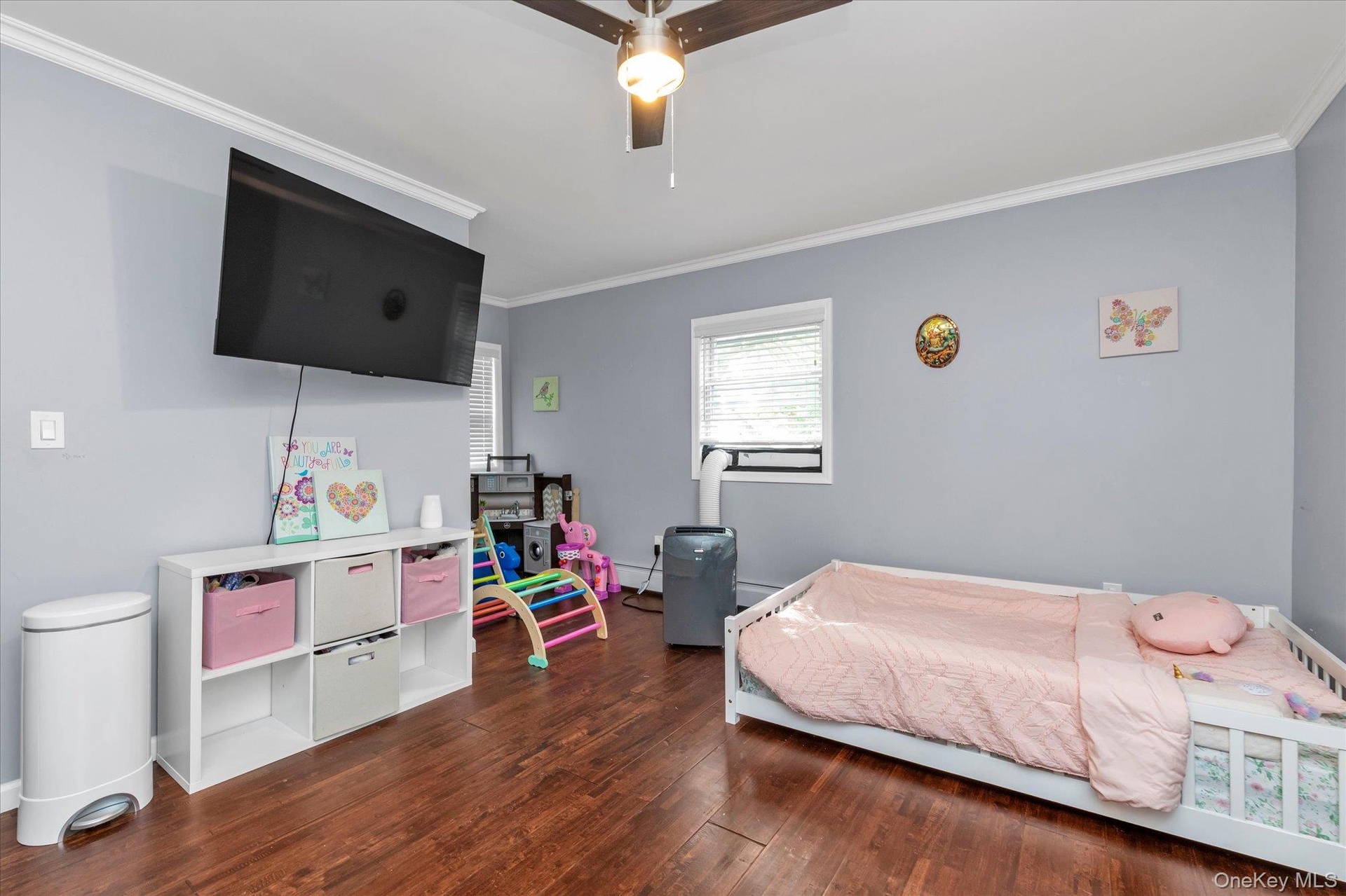 Interior space featuring wood-finish flooring, crown molding, and a central ceiling fan with integrated lighting