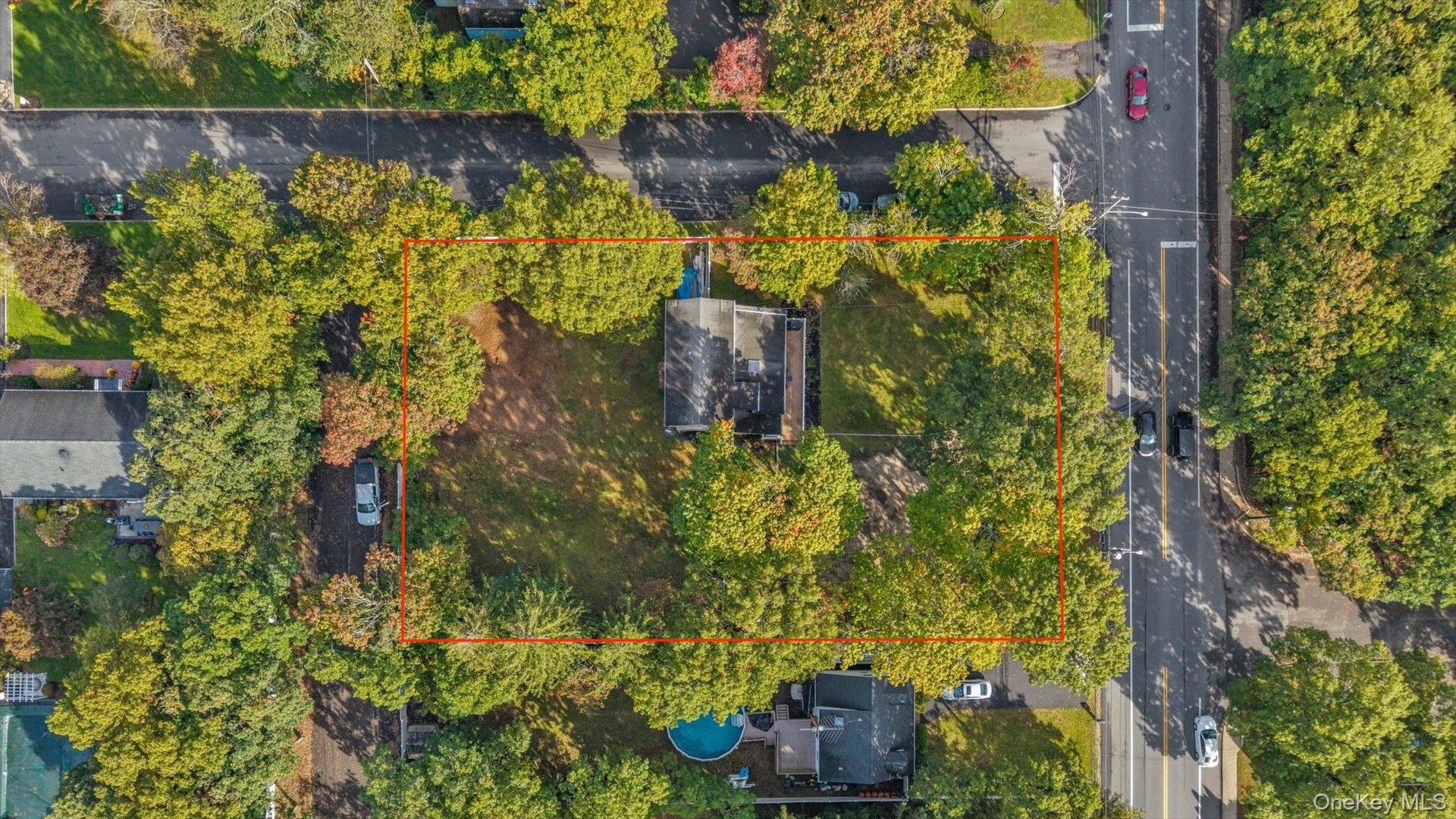 Aerial perspective of a corner lot featuring extensive lawn space, mature perimeter trees, and a detached structure