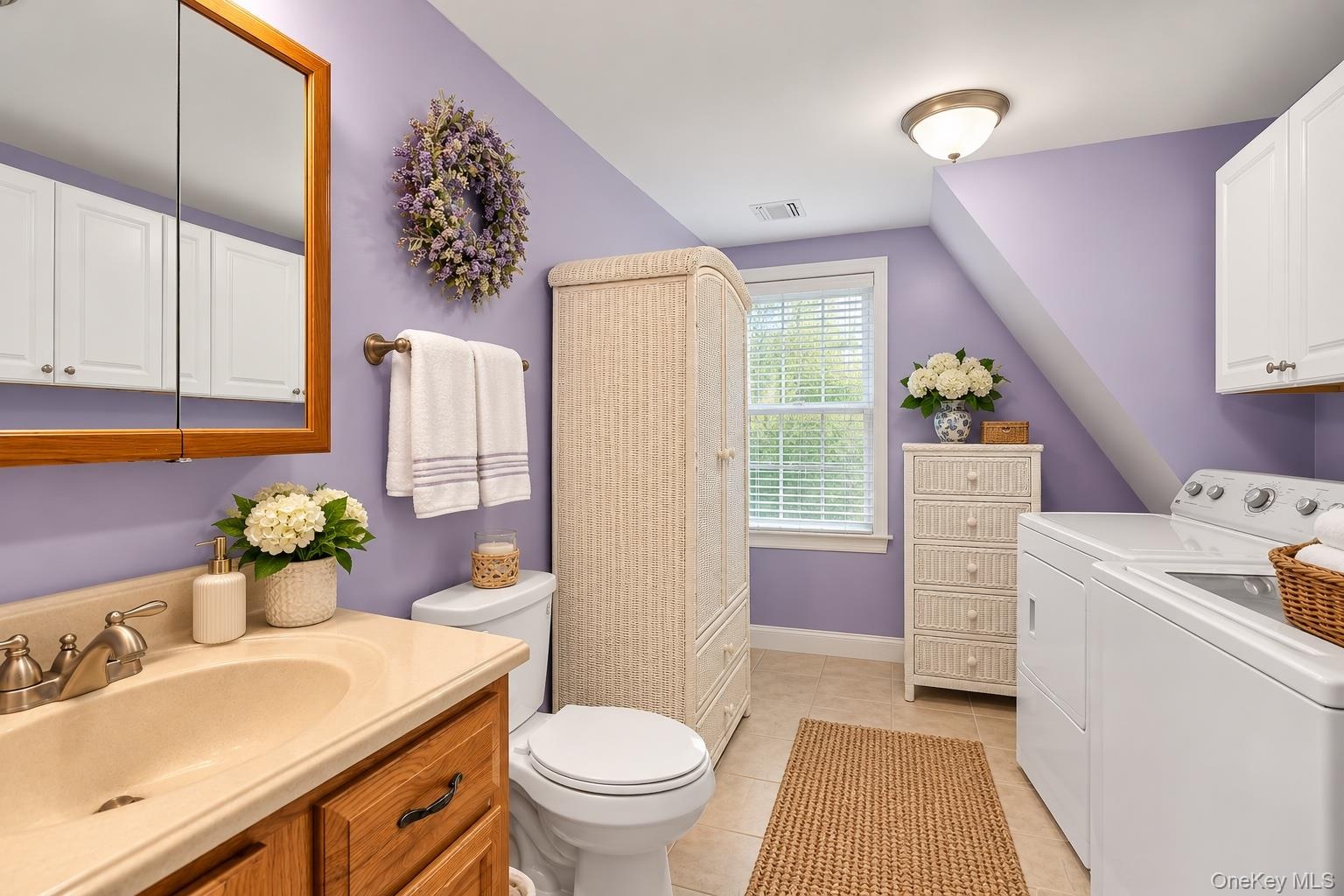 Bathroom featuring wood-finish vanity cabinetry, integrated sink with metallic faucet, medicine cabinet, dual-door wall-mounted storage, and tile floo